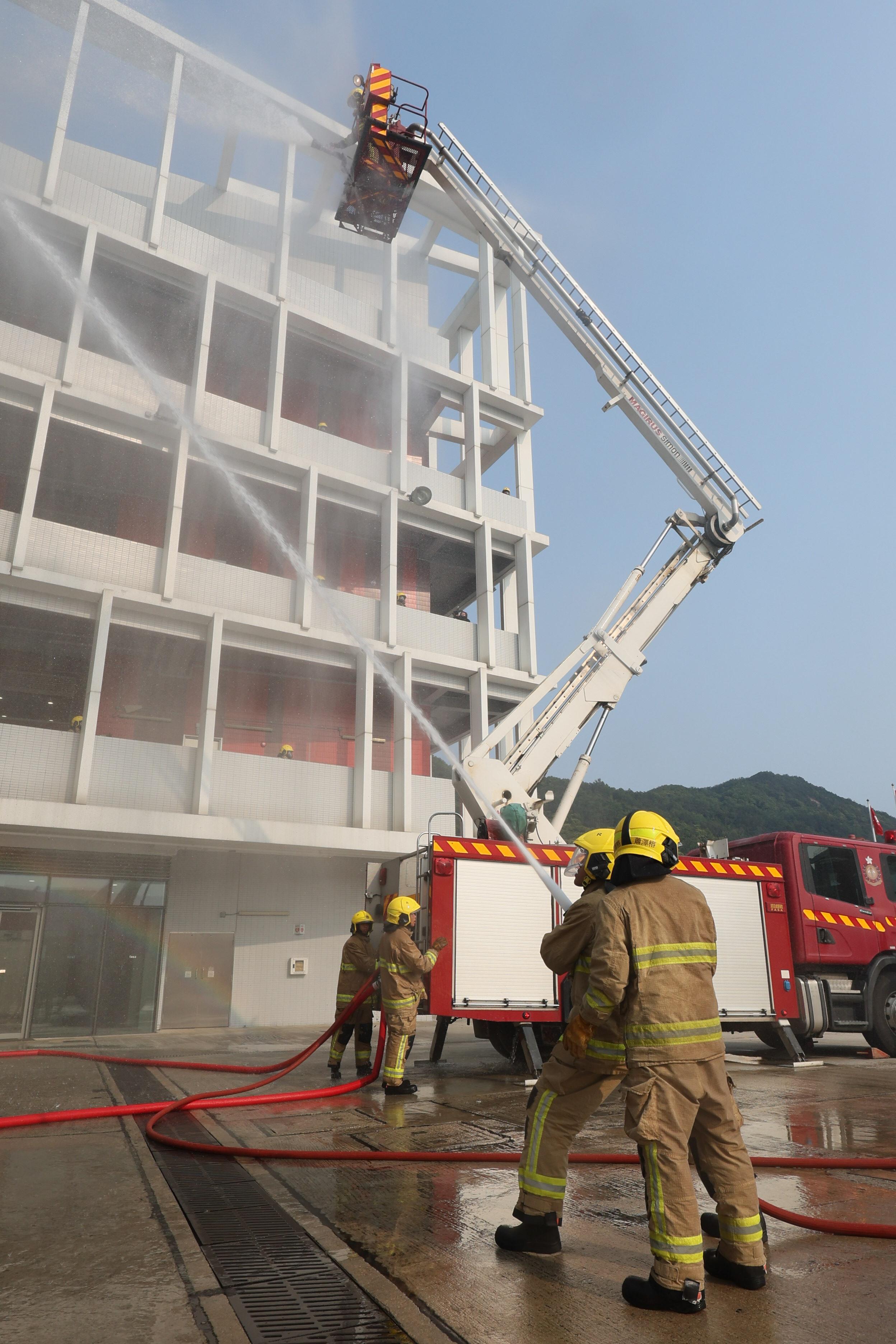 財政司司長陳茂波今日（三月八日）在消防及救護學院舉行的消防處結業會操檢閱學員。圖示結業學員示範模擬撲滅火警工作。 