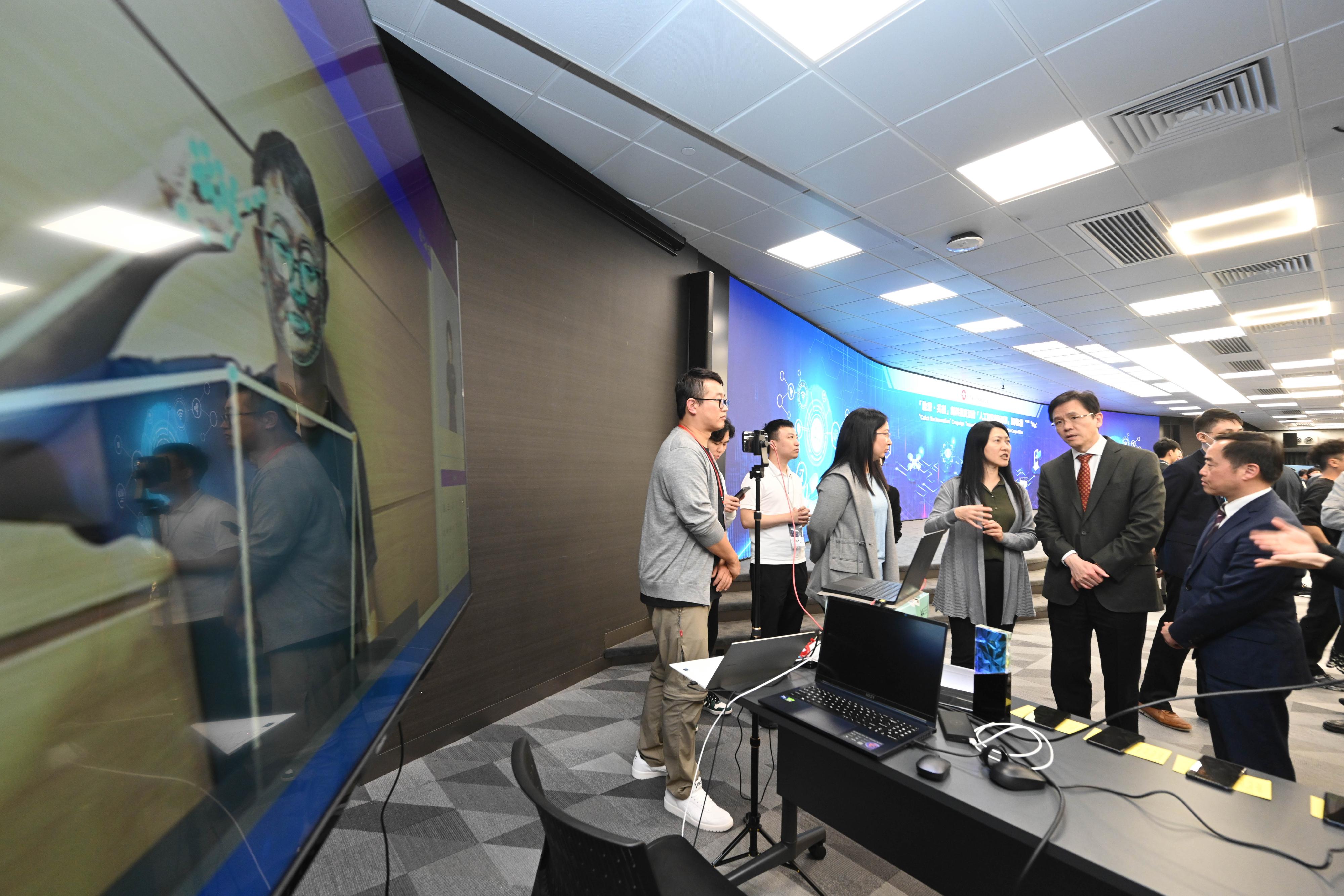 The Secretary for Innovation, Technology and Industry, Professor Sun Dong (second right), is briefed on the grand award project "Improving communications through generative sign language" at the Award Presentation Ceremony for the "Innovative Application with AI" Innovation Competition today (March 15). Looking on is the Government Chief Information Officer, Mr Tony Wong (first right).