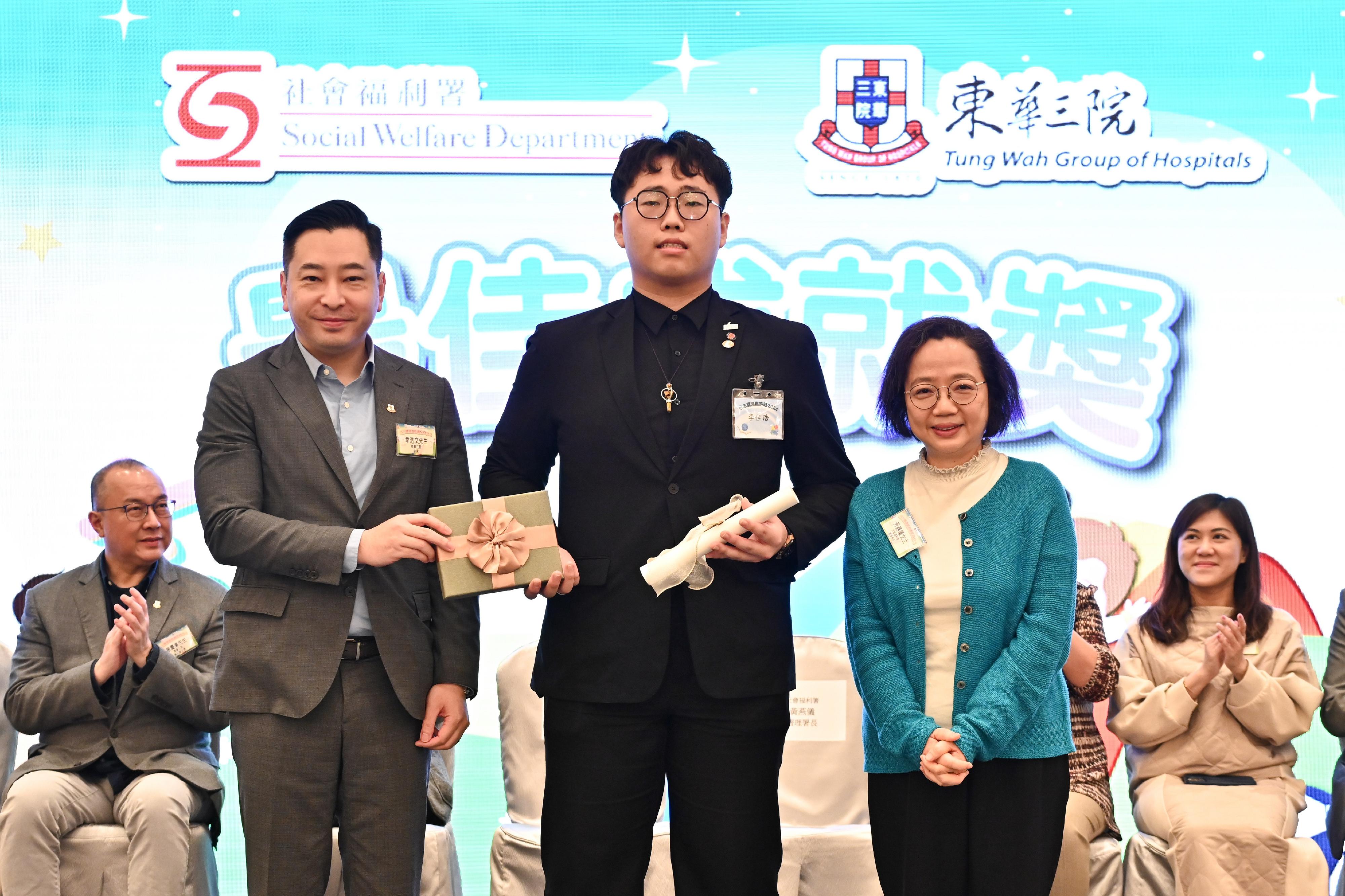 The Acting Director of Social Welfare (DSW), Ms Wong Yin-yee (right), and the Chairman of the Board of Directors of the Tung Wah Group of Hospitals, Mr Herman Wai (left), present a certificate to an awardee (centre) of the Best Achievement Award at the 2024 Award Presentation Ceremony for DSW wards today (March 16).