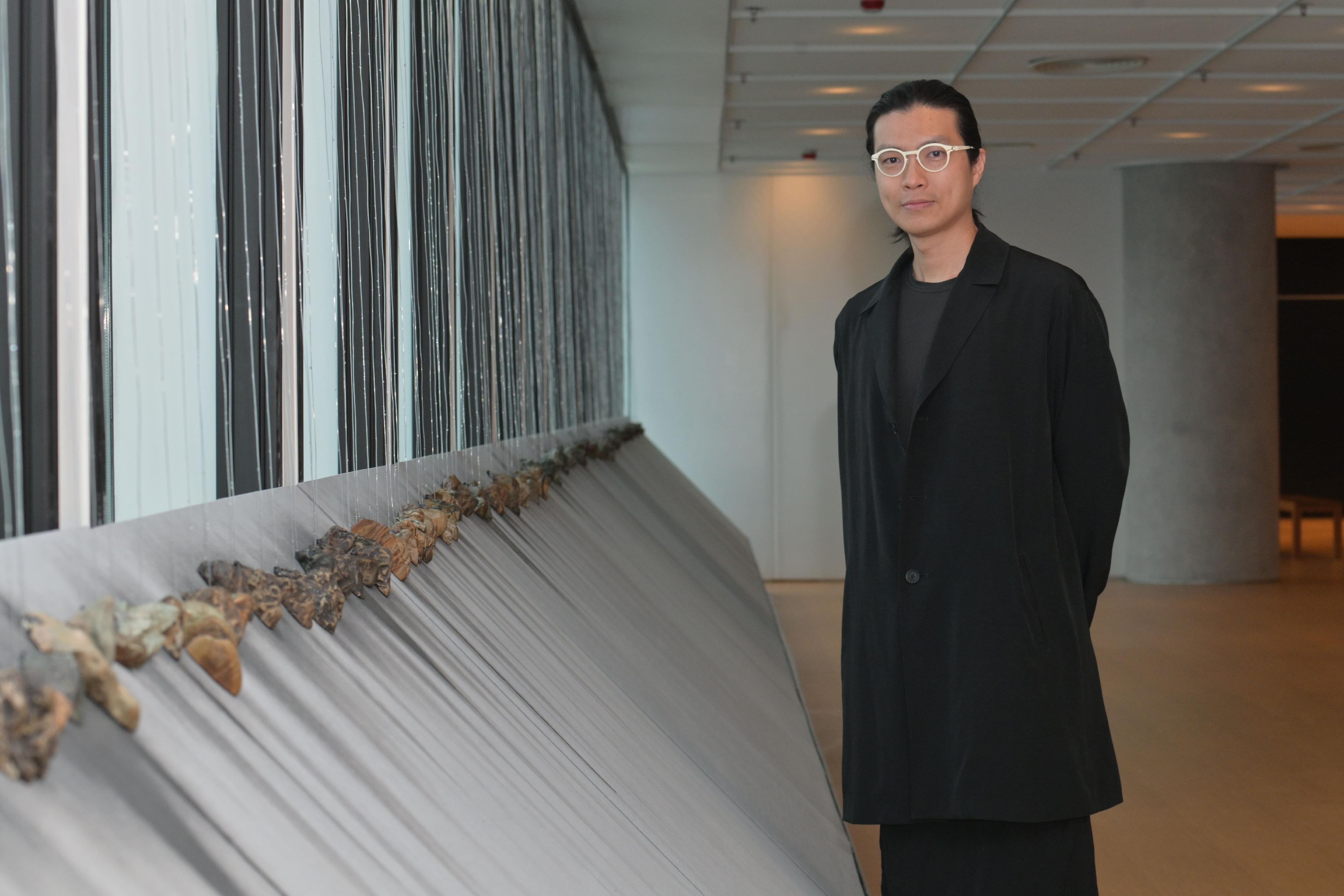 香港藝術家張瀚謙及其創作的場域特定藝術裝置《瀑林》。這作品以降雨量數據作指引，由機械裝置將水引至半空再滴落特製畫布上，幻化成的「墨跡」組成一幅幅動態水墨瀑布。