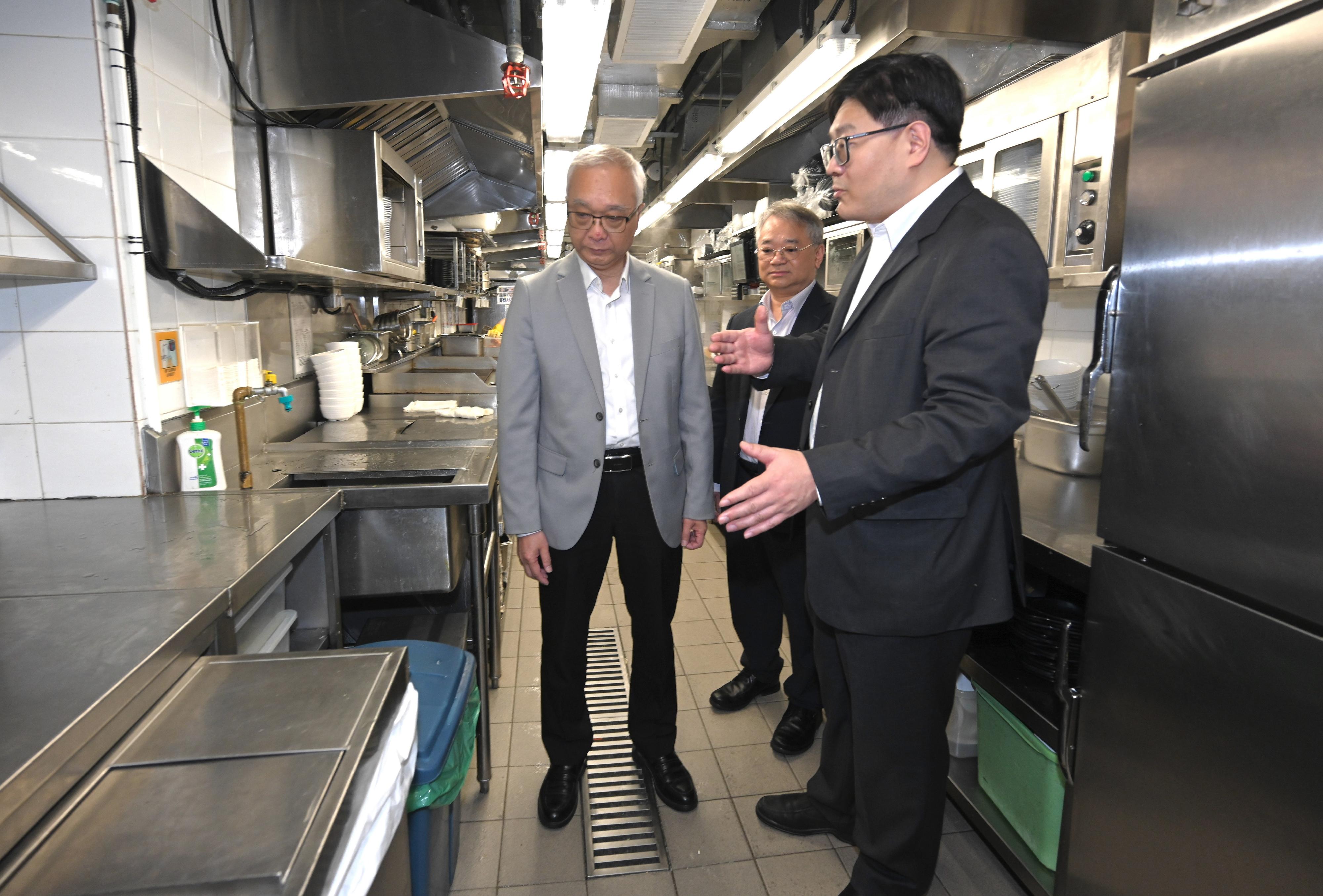 The Secretary for Environment and Ecology, Mr Tse Chin-wan, today (March 27) inspected various premises under the Municipal Solid Waste Charging Demonstration Scheme to understand the premises' preparatory work. Photo shows Mr Tse (left) and the Director of Environmental Protection, Dr Samuel Chui (centre), inspecting the process of a fast food restaurant chain's kitchen in handling waste and learning about the practical arrangements and requirements of the preparatory work for the Demonstration Scheme.