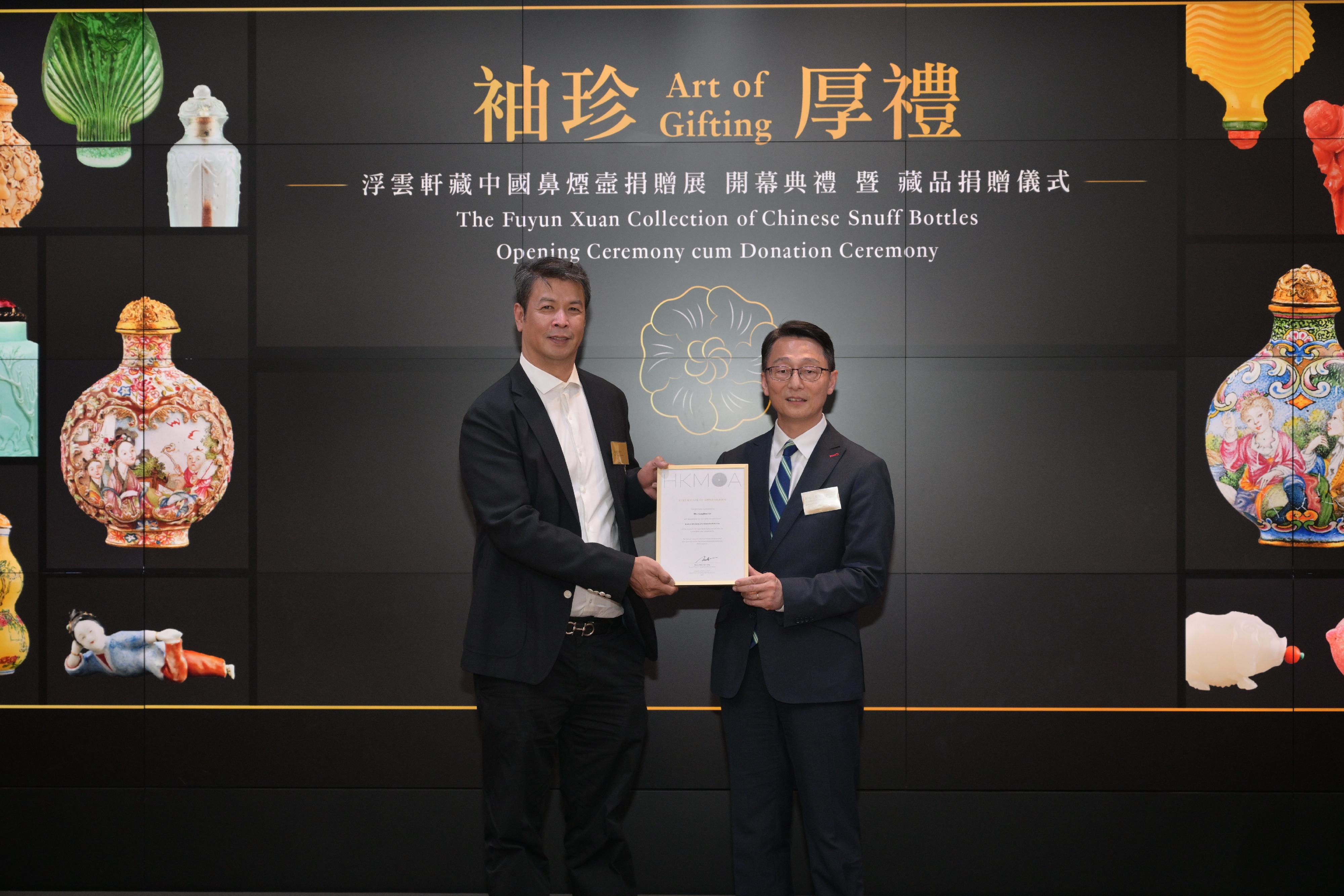 The opening ceremony of the "Art of Gifting: The Fuyun Xuan Collection of Chinese Snuff Bottles" exhibition and donation ceremony was held today (April 11) at the Hong Kong Museum of Art. Photo shows the Director of Leisure and Cultural Services, Mr Vincent Liu (right), presenting a Certificate of Appreciation to the son of Mr Christopher Sin and Mrs Josephine Sin, Mr Nicholas Sin.