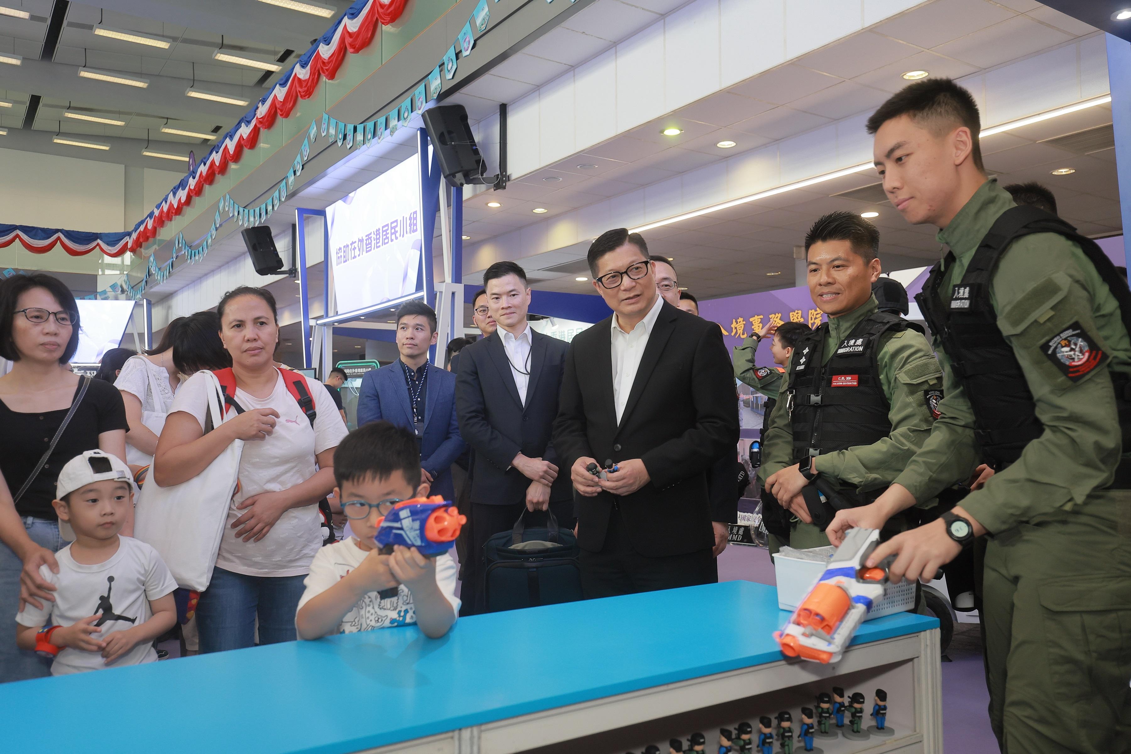 To support the National Security Education Day, the Immigration Service Institute of Training and Development held an open day today (April 13). Photo shows the Secretary for Security, Mr Tang Ping-keung (third right), visiting an exhibition booth and interacting with the public. 