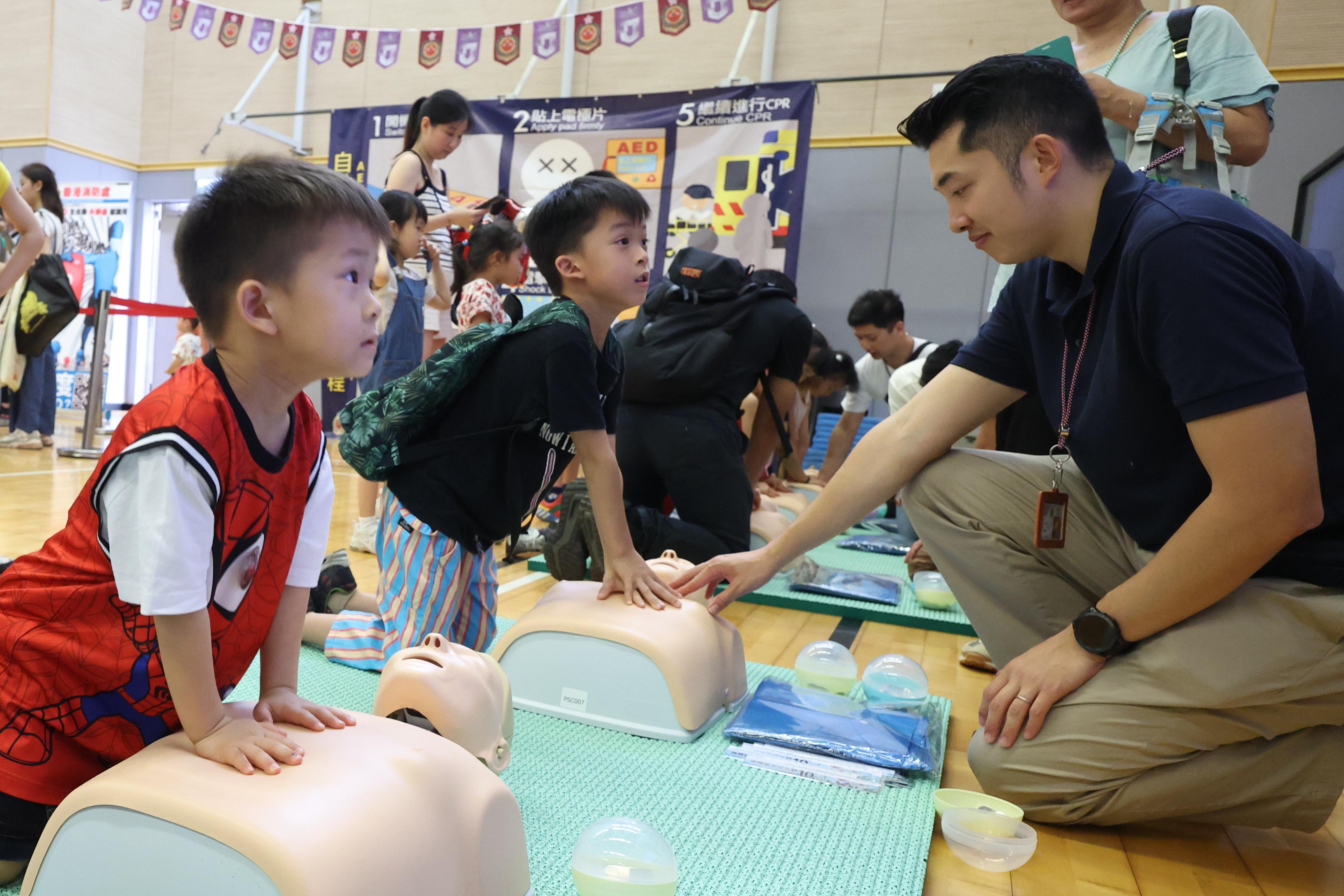 In response to and support of National Security Education Day, the Fire Services Department held an open day at the Fire and Ambulance Services Academy in Tseung Kwan O today (April 14). Photo shows visitors learning administration of cardiopulmonary resuscitation under the instruction of ambulance personnel.