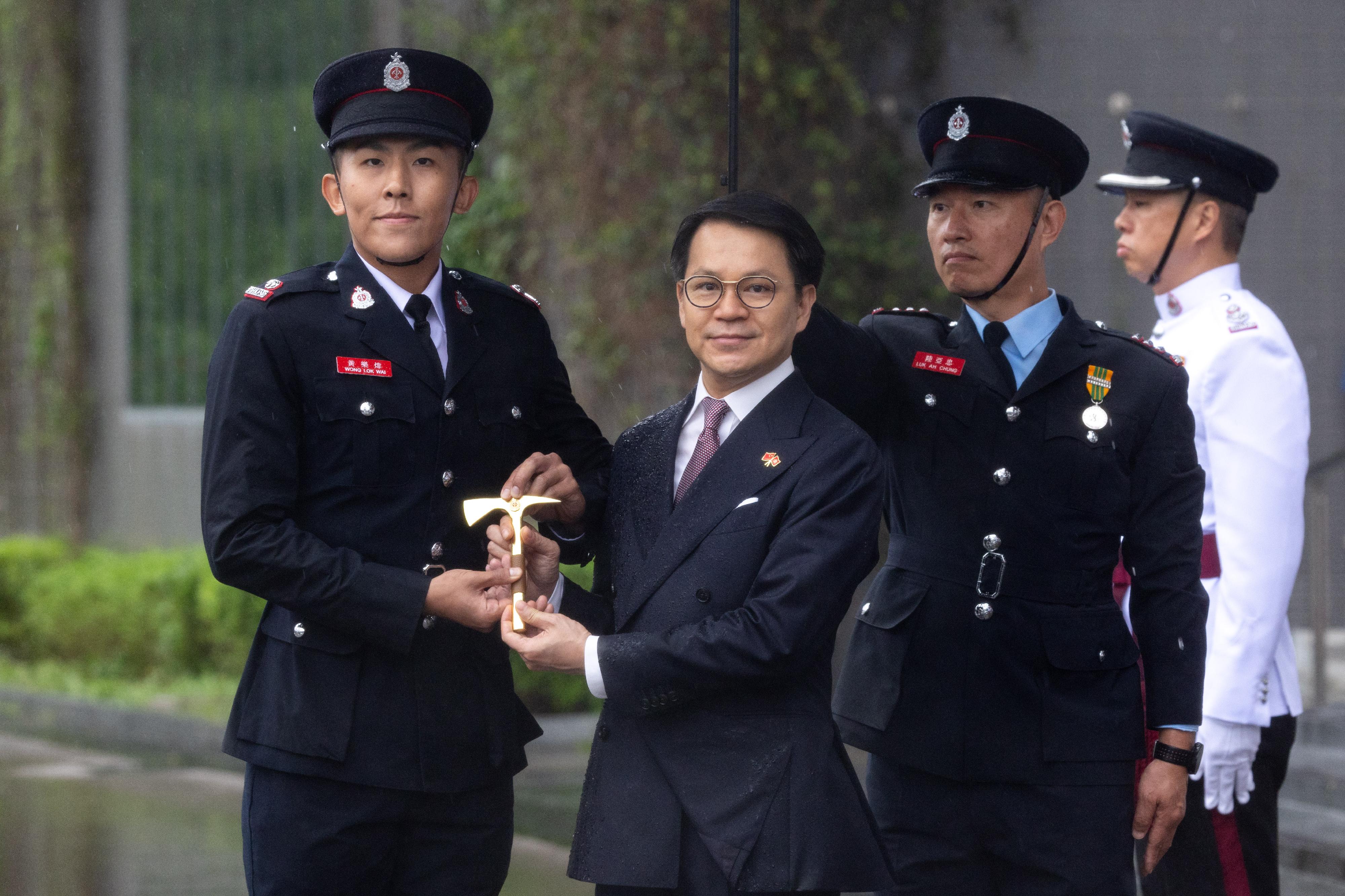 The Chairman of the Legislative Council Panel on Security, Mr Chan Hak-kan, reviewed the Fire Services passing-out parade at the Fire and Ambulance Services Academy today (May 24). Photo shows Mr Chan (second left) presenting the Best Recruit Station Officer award to a graduate.