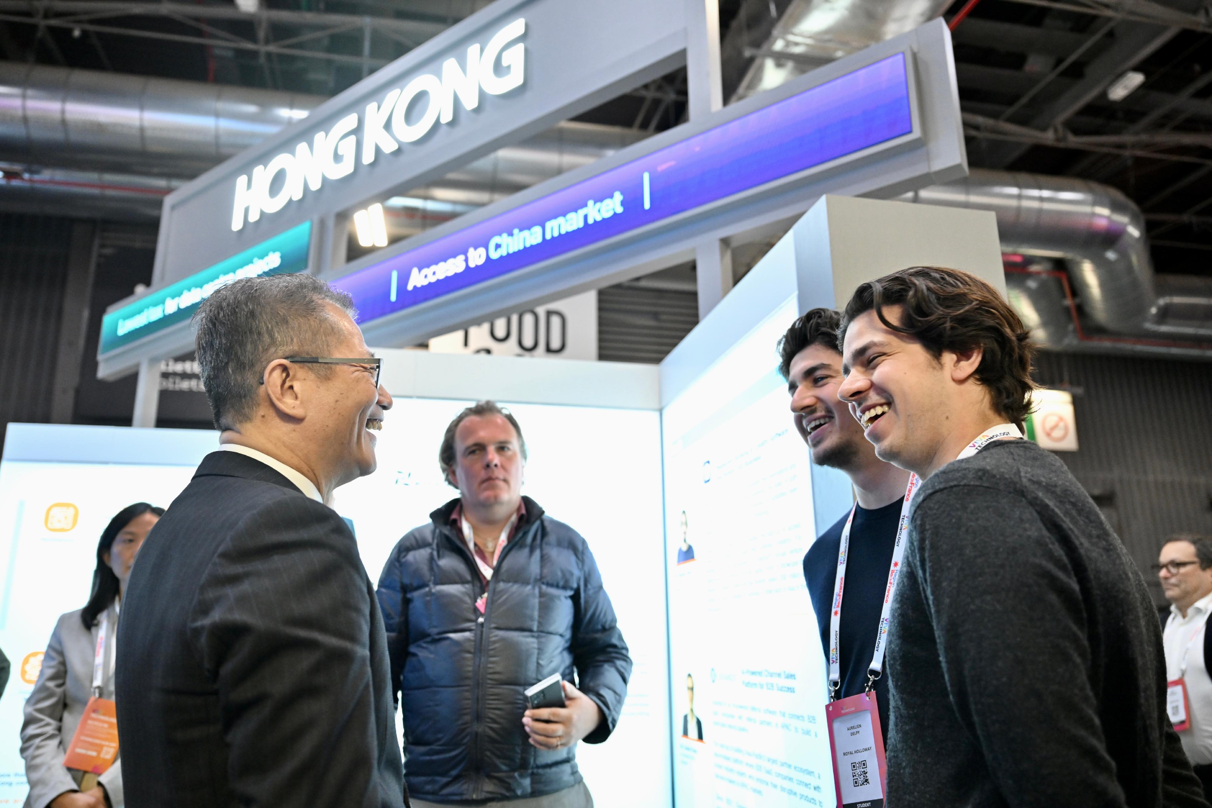 陳茂波（左一）到訪展覽會的香港館，與參展的香港企業代表交談。