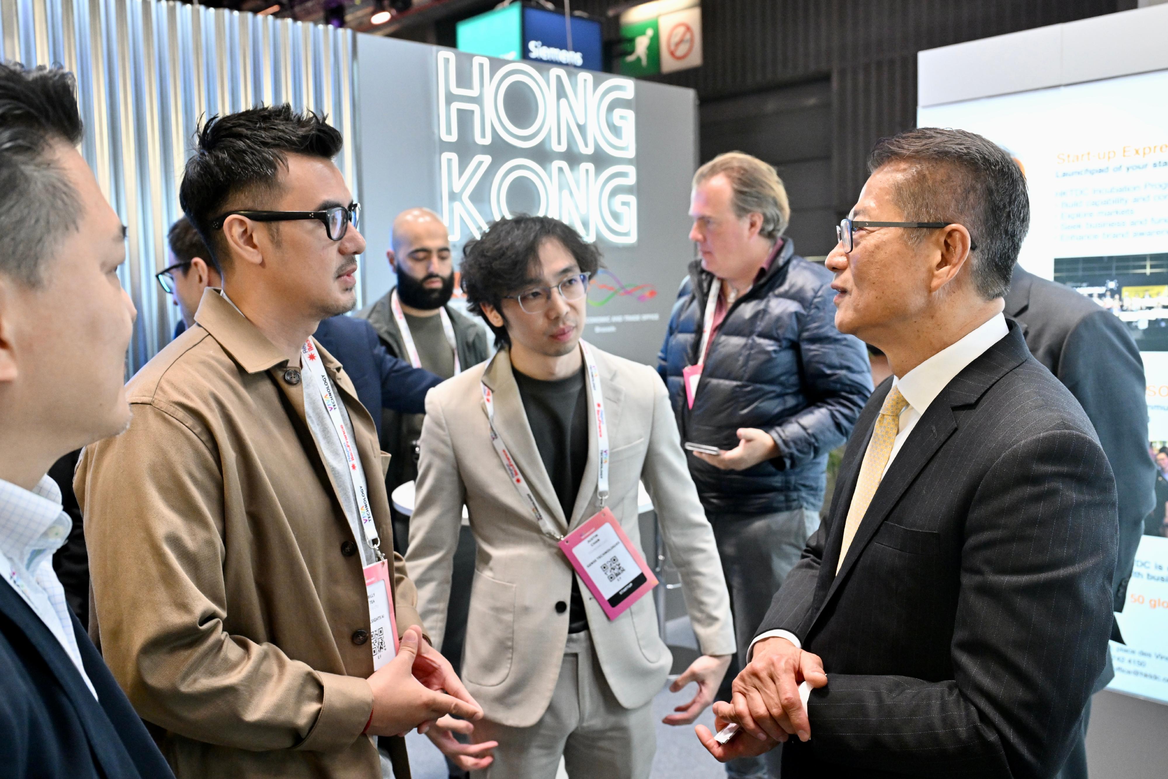 陳茂波（右一）到訪展覽會的香港館，與參展的香港企業代表交談。