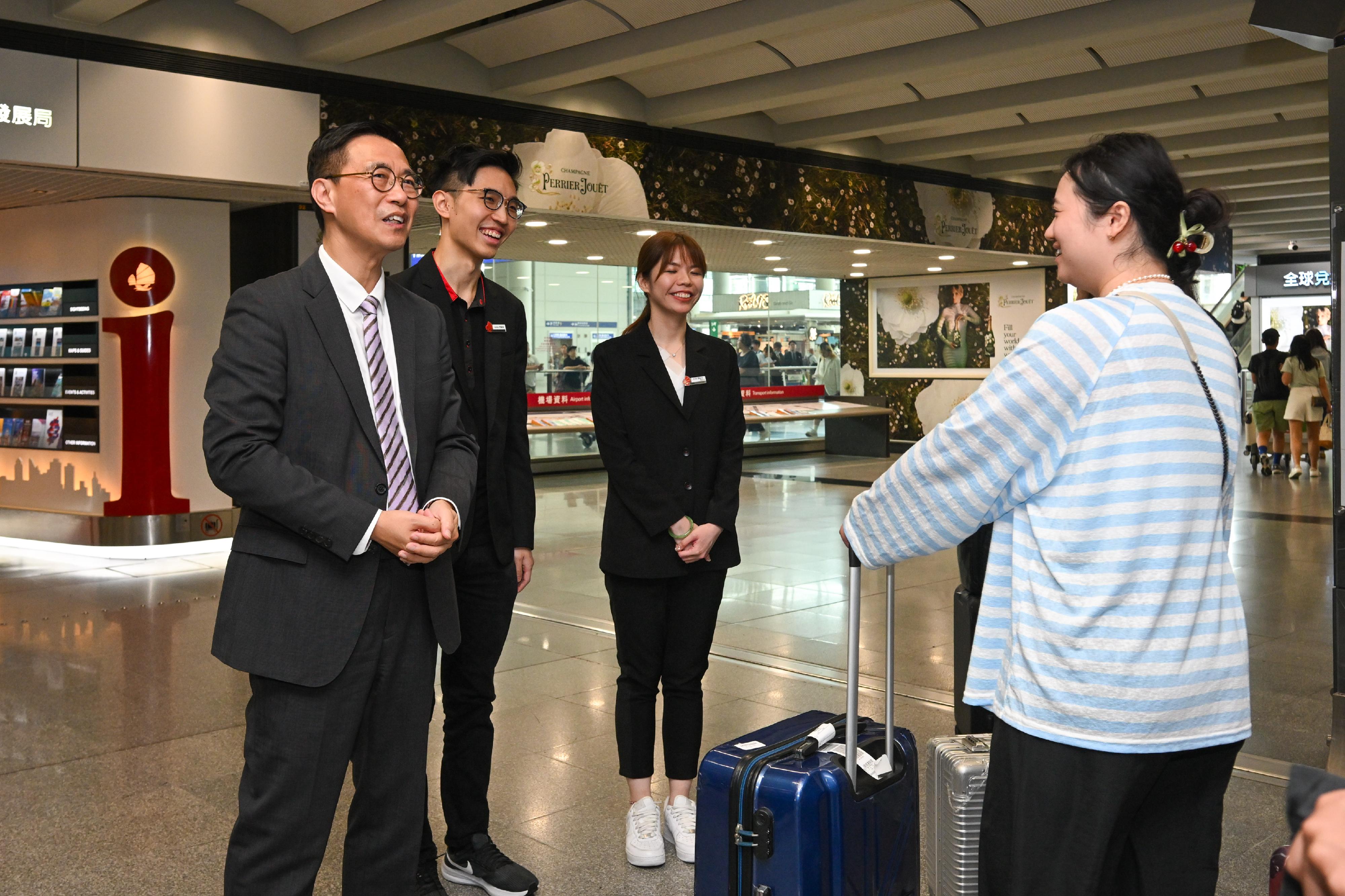 文化体育及旅游局局长杨润雄今日（五月二十七日）到香港国际机场视察香港旅游发展局位于香港国际机场的旅客谘询中心。图示杨润雄（左一）欢迎来自内地的自由行旅客，并与他们交谈。