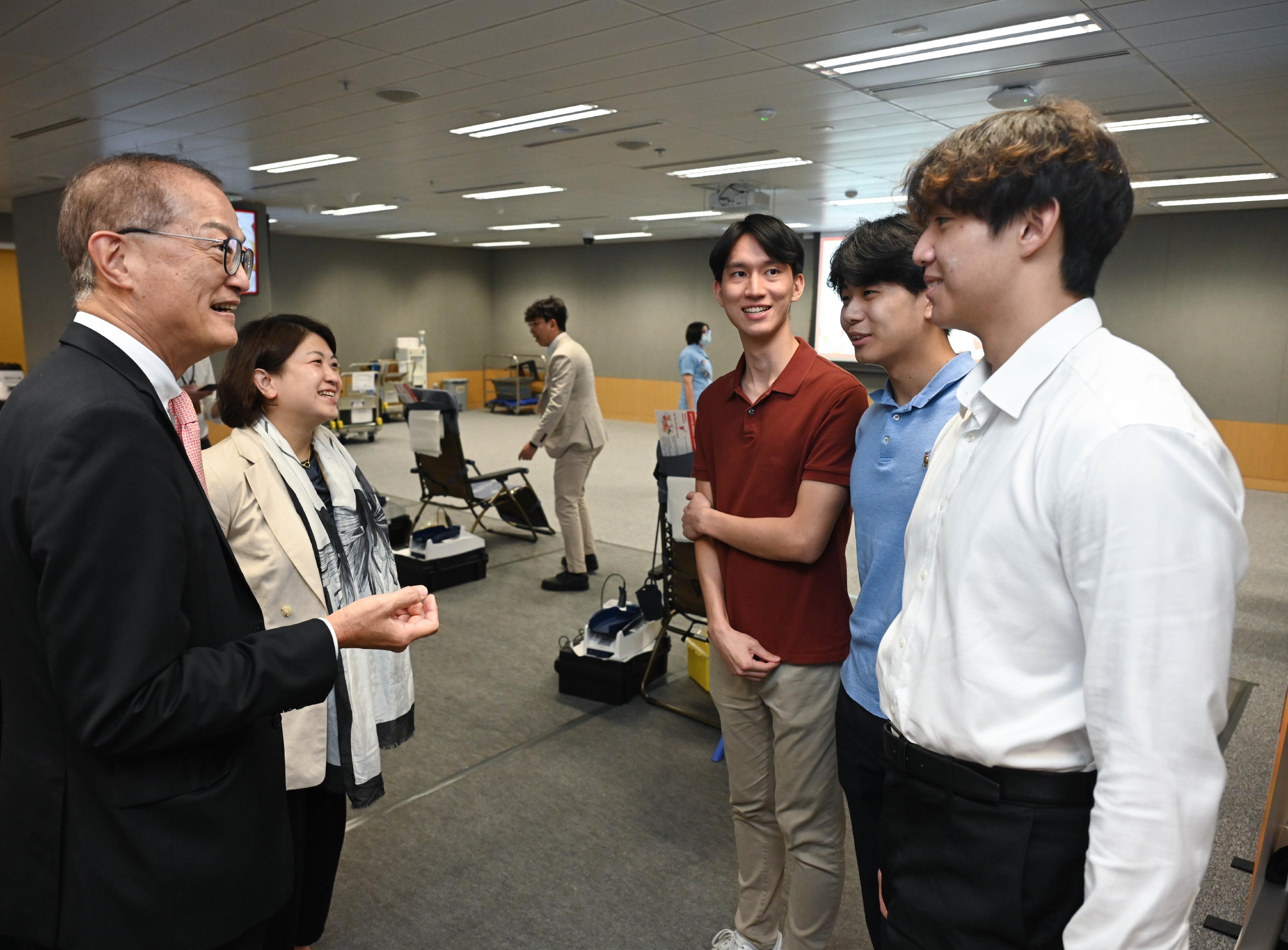 The Secretary for Health, Professor Lo Chung-mau, and the Under Secretary for Health, Dr Libby Lee, donated blood at the blood donation drive being held by the Hong Kong Red Cross in the Central Government Offices today (June 13). Photo shows Professor Lo (first left) and Dr Lee (second left) chatting with three participating medical students.