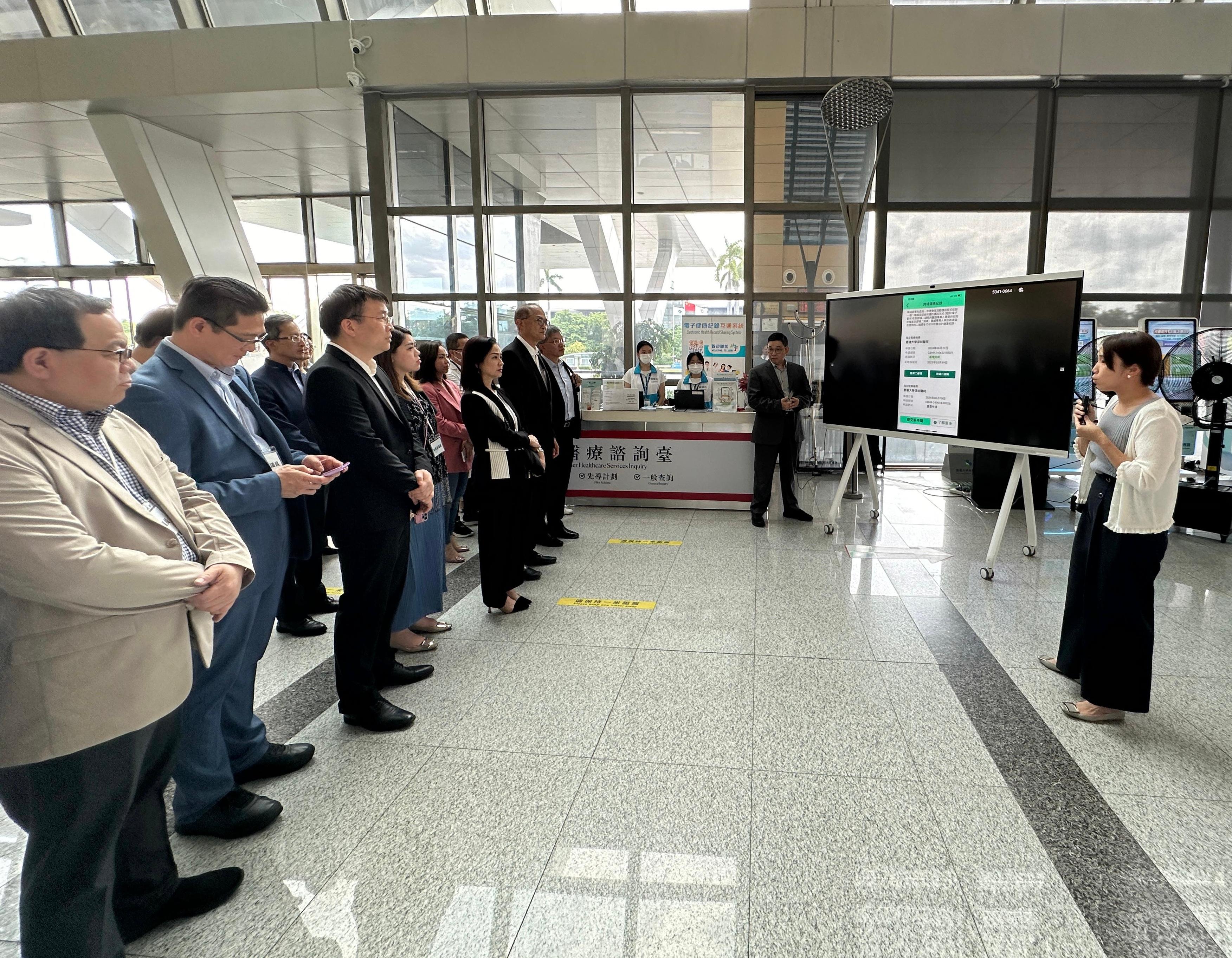 The Secretary for Health, Professor Lo Chung-mau, led a delegation comprising representatives of the Health Bureau (HHB), the Department of Health and the Hospital Authority, together with Legislative Council (LegCo) Members to visit the University of Hong Kong-Shenzhen Hospital (HKU-SZH) today (June 22). During the visit, HHB personnel introduced to the LegCo Members about the two new functions of the eHealth mobile application which will be on trial at HKU-SZH from July 15 to facilitate cross-boundary medical collaboration. Photo shows Professor Lo (front row, sixth left); The Permanent Secretary for Health, Mr Thomas Chan (front row, seventh left); the Chairman of the LegCo Panel on Health Services, Ms Chan Hoi-yan (front row, fifth left); and other LegCo Members learning about the usage of the new functions and how the safety of users' medical data are protected.