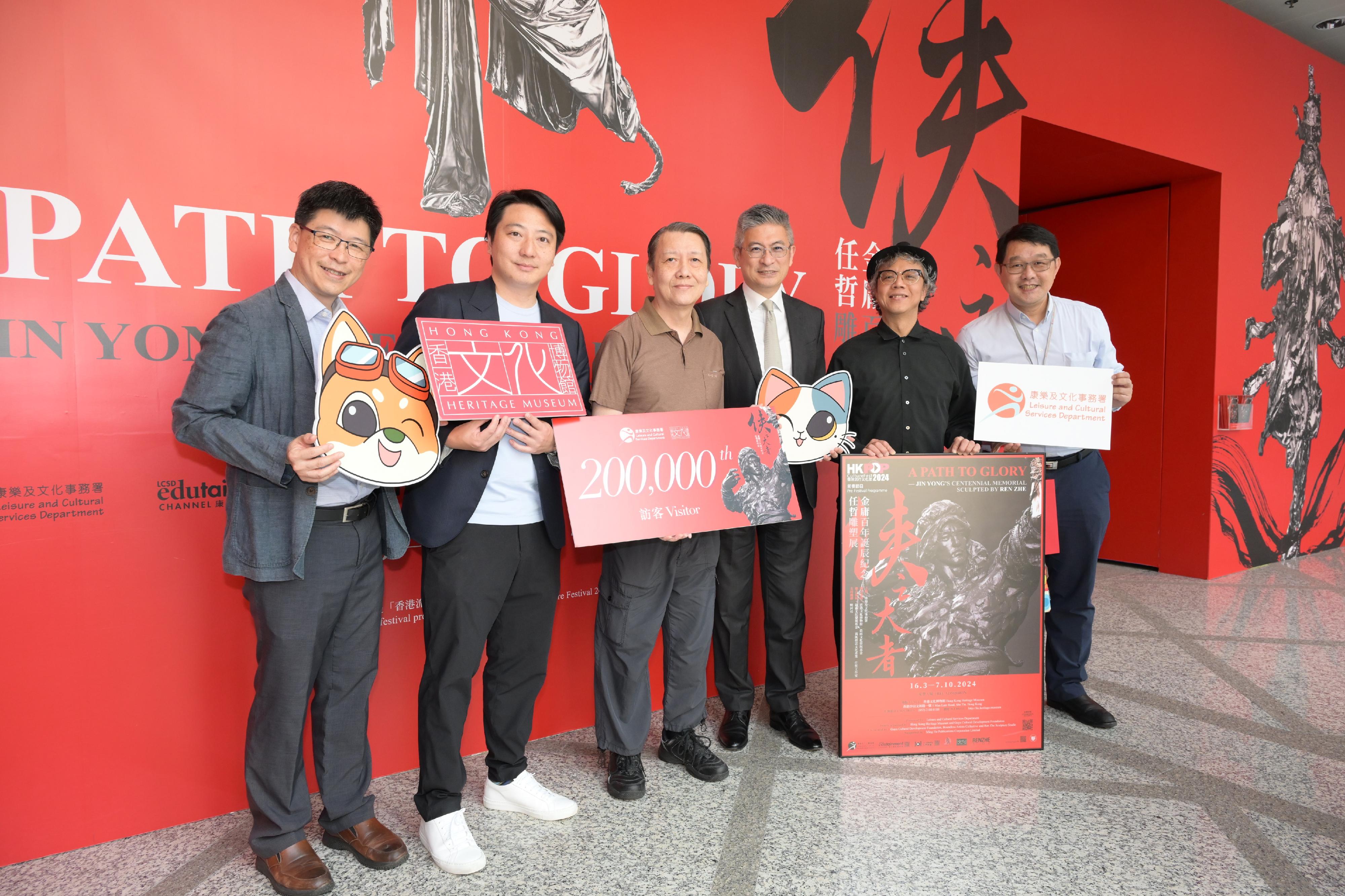 The "A Path to Glory - Jin Yong's Centennial Memorial, Sculpted by Ren Zhe" exhibition at the Hong Kong Heritage Museum (HKHM) has reached 200 000 visitors since its opening on March 16. Photo shows the Under Secretary for Culture, Sports and Tourism, Mr Raistlin Lau (third right); the Founder of Guyu Cultural Development Foundation and the co-curator of the exhibition, Mr William Fong (second left); the multimedia artist of the exhibition, Mr Victor Wong (second right); the Museum Director of the HKHM, Mr Brian Lam (first right); and the Curator (Art) of the HKHM, Dr Raymond Tang (first left), welcoming the 200 000th visitor of the exhibition and presenting a gift pack to the visitor yesterday (June 21).