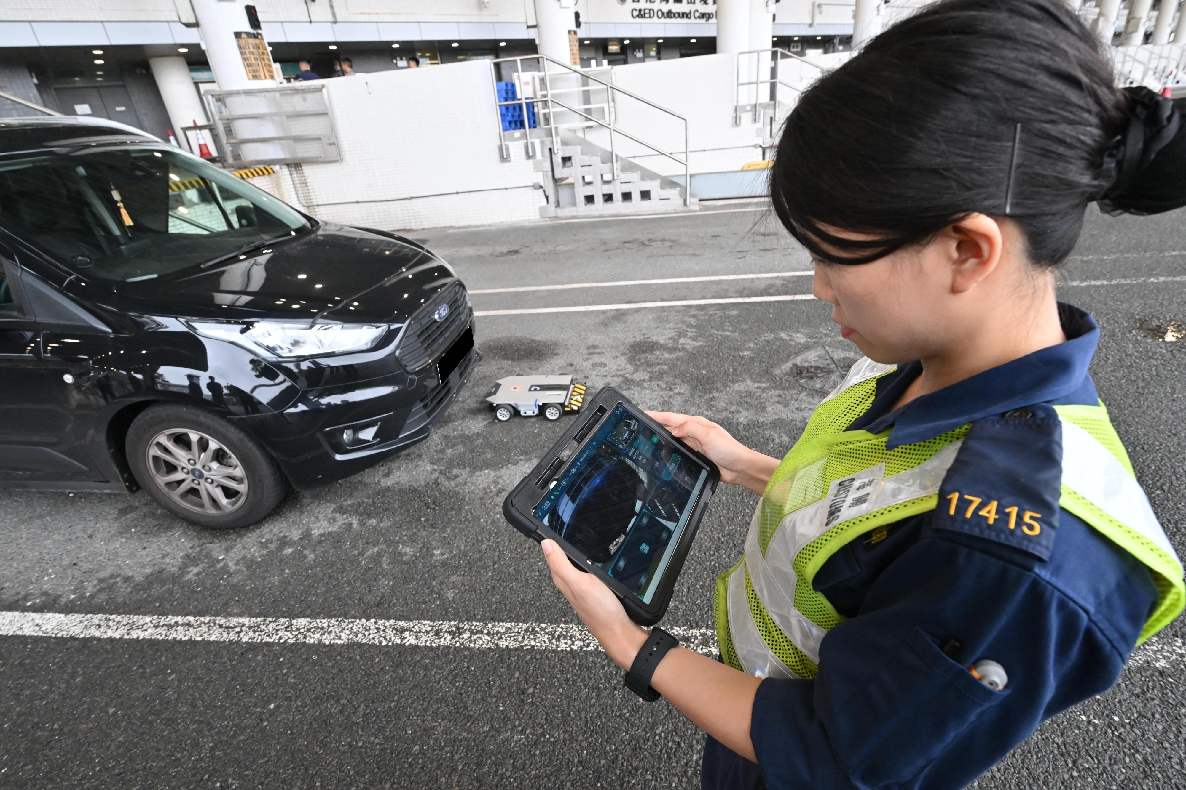 Hong Kong Customs and the Fire Services Department co-organised a counter-terrorism intelligence and hazardous material incident exercise codenamed "WOLFHUNT" this afternoon (June 24) at the Shenzhen Bay Control Point. Photo shows a Customs officer making use of the recently introduced Smart Under Vehicle Robot to assist in cross-boundary vehicle inspections.