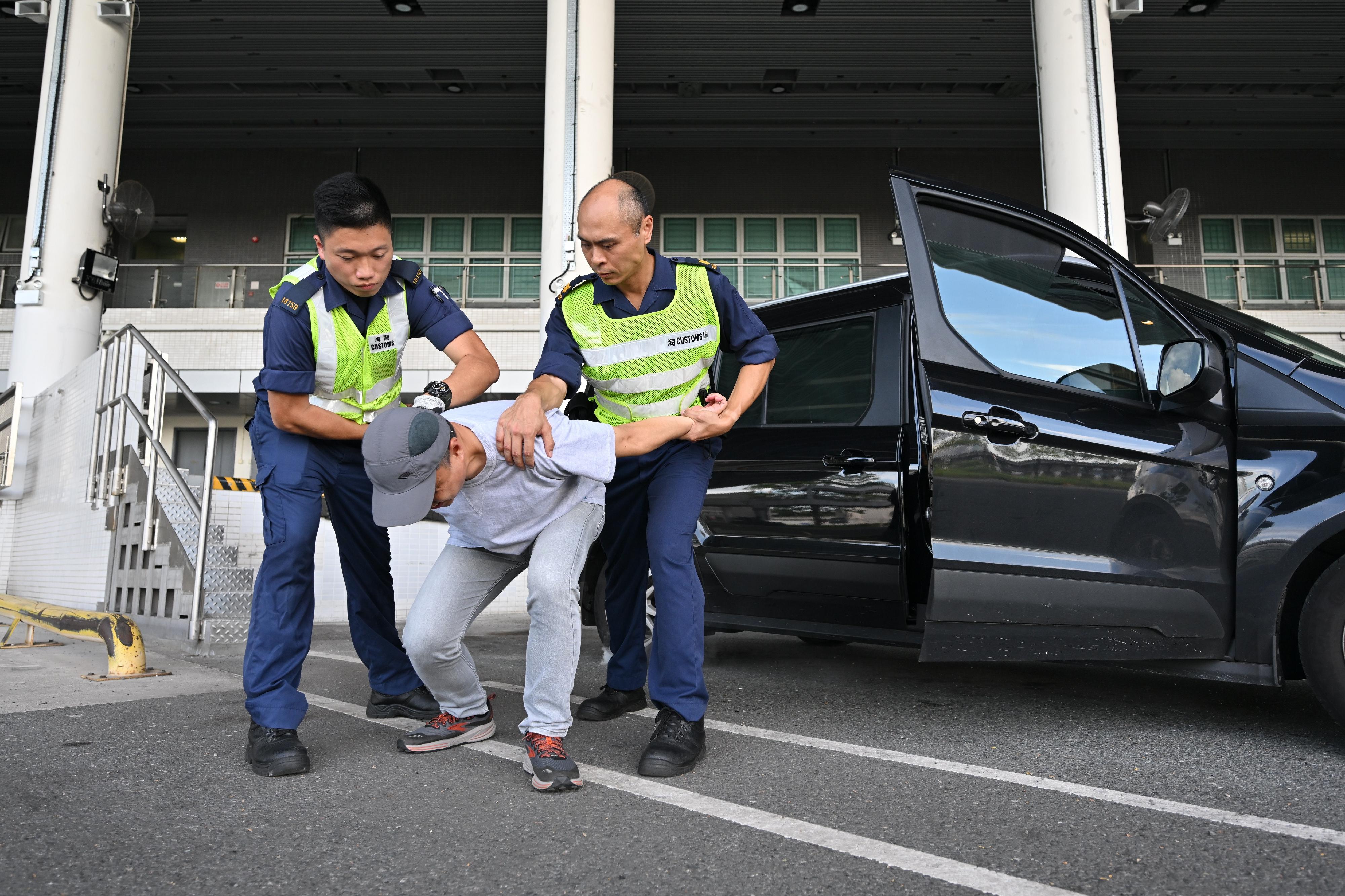 Hong Kong Customs and the Fire Services Department co-organised a counter-terrorism intelligence and hazardous material incident exercise codenamed "WOLFHUNT" this afternoon (June 24) at the Shenzhen Bay Control Point. Photo shows Customs officers subduing a light goods vehicle driver who was suspected to be involved in terrorist activities.
