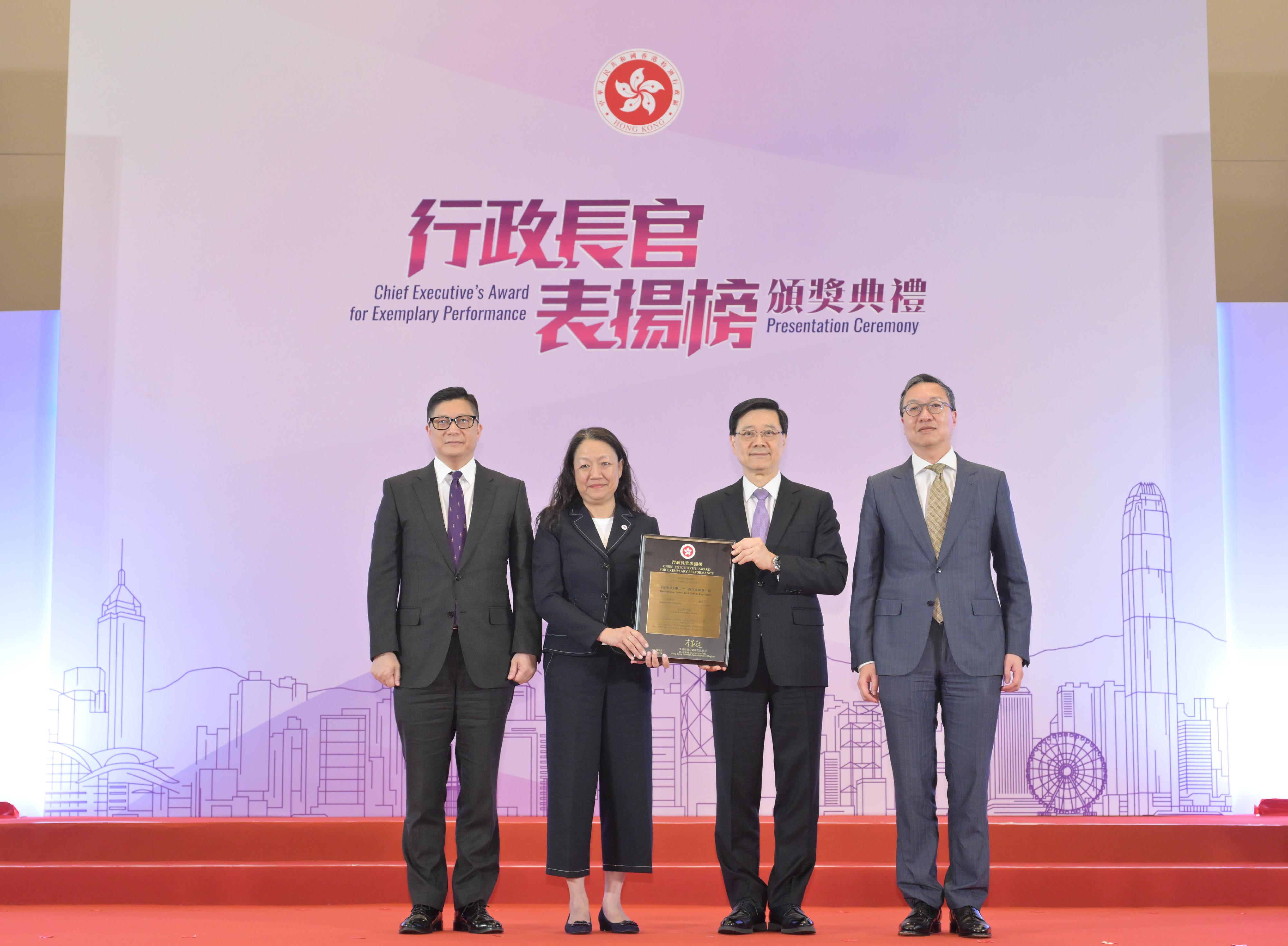 The Chief Executive, Mr John Lee, officiated at the Chief Executive's Award for Exemplary Performance Presentation Ceremony today (June 26) to present an award certificate to the Task Force on Basic Law Article 23 Legislation comprising the Department of Justice, the Security Bureau, and the Hong Kong Police Force. Photo shows Mr Lee (second right) presenting an award certificate to the representative of the Task Force and the then Deputy Secretary for Security, Mrs Apollonia Liu (second left). Looking on are the Secretary for Justice, Mr Paul Lam, SC (first right), and the Secretary for Security, Mr Tang Ping-keung (first left).