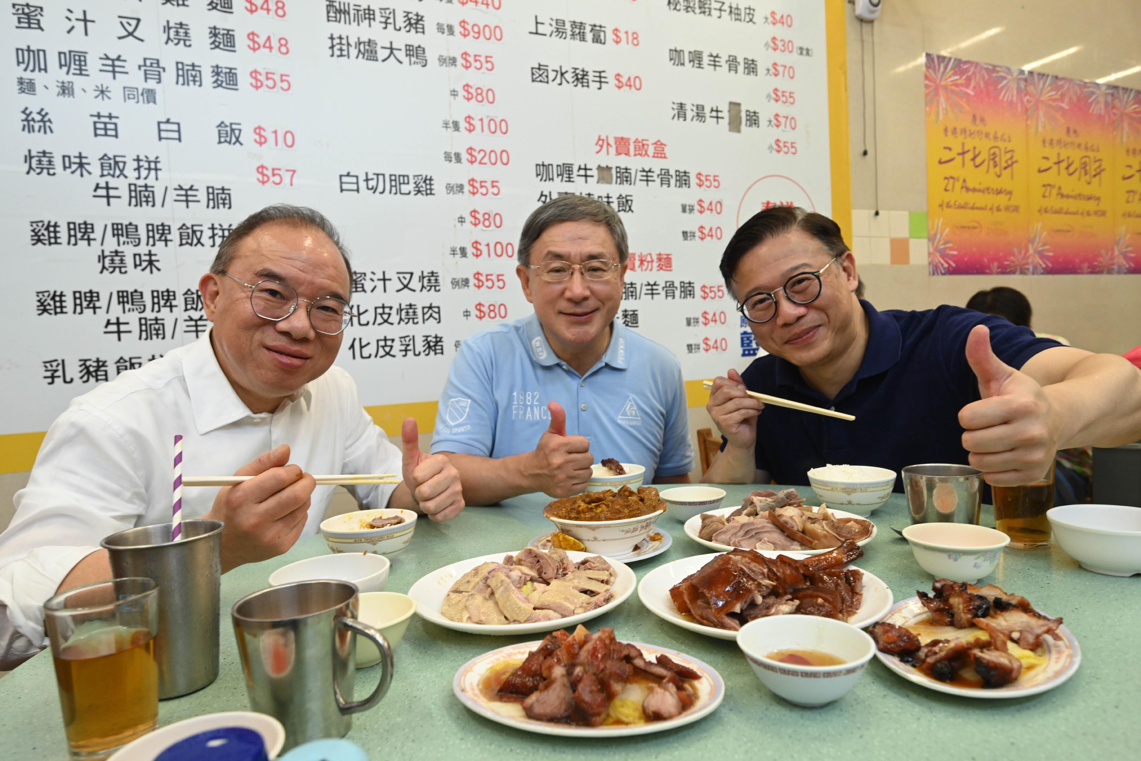 The Acting Chief Secretary for Administration, Mr Cheuk Wing-hing (centre); the Deputy Secretary for Justice, Mr Cheung Kwok-kwan (right); and the Secretary for Constitutional and Mainland Affairs, Mr Erick Tsang Kwok-wai (left), enjoy dining discounts to celebrate Hong Kong's return to the motherland with members of the public at the Wan Chai Bowrington Road Cooked Food Centre today (July 1).