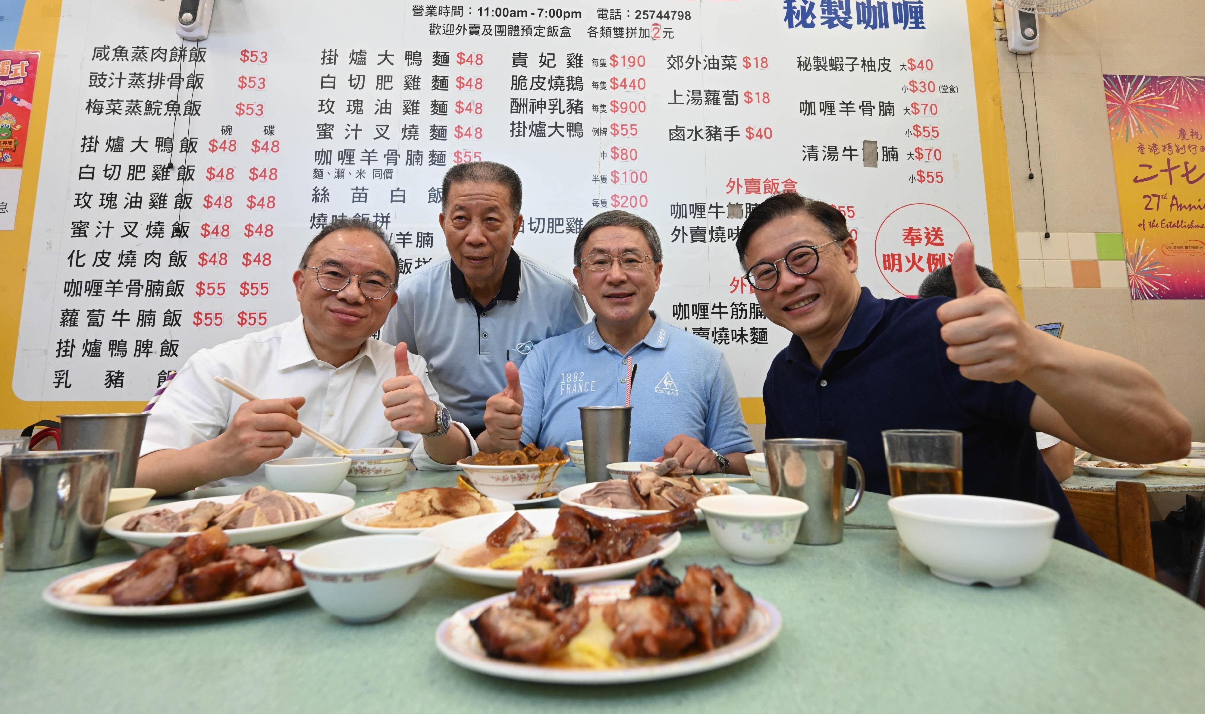 The Acting Chief Secretary for Administration, Mr Cheuk Wing-hing (centre); the Deputy Secretary for Justice, Mr Cheung Kwok-kwan (right); and the Secretary for Constitutional and Mainland Affairs, Mr Erick Tsang Kwok-wai (left), are pictured with a stall owner at the Wan Chai Bowrington Road Cooked Food Centre today (July 1).