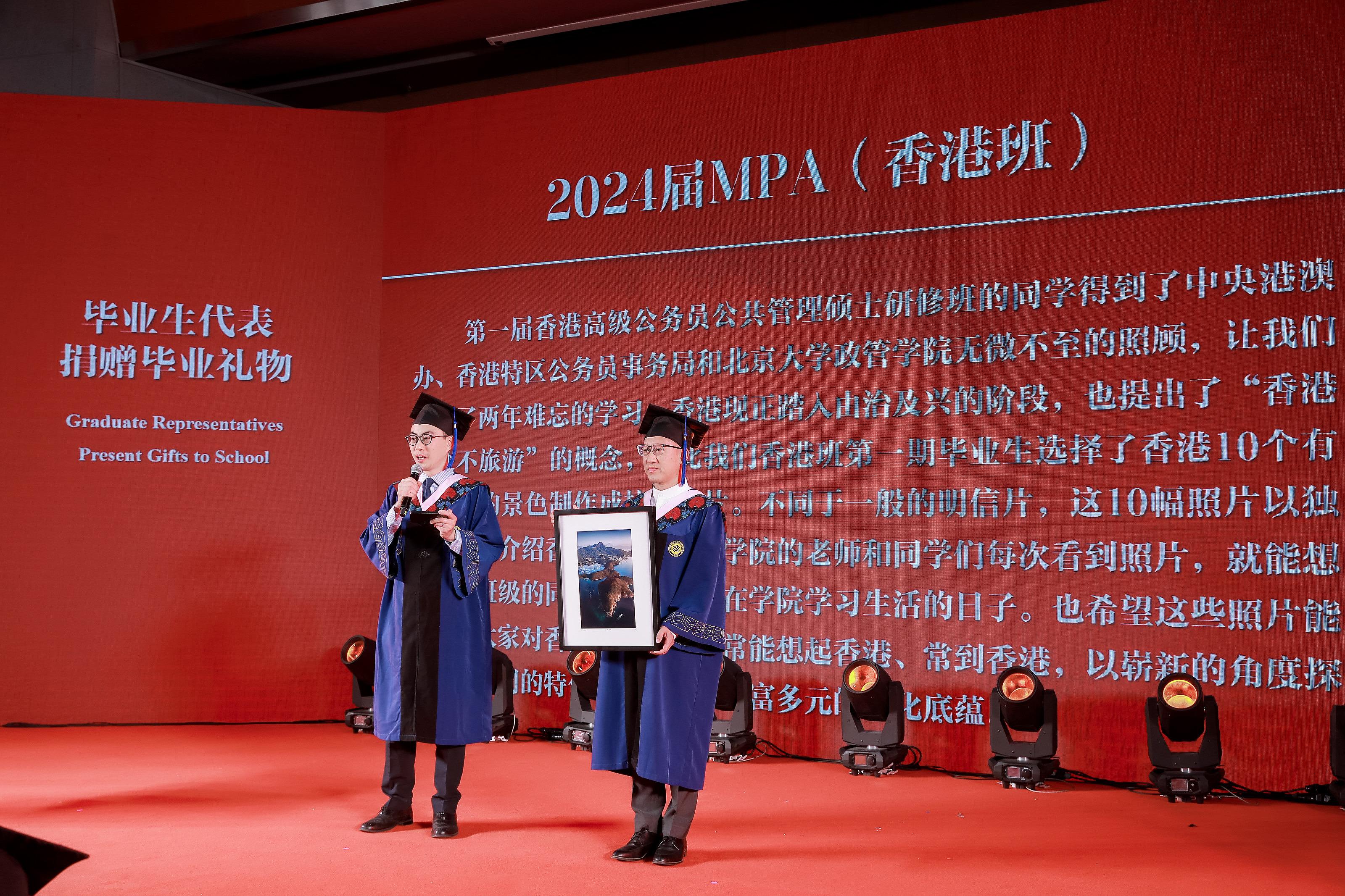 The inaugural cohort of the Master's Degree in Public Policy Programme for senior civil servants of the Hong Kong Special Administrative Region (HKSAR) Government graduated today (July 3). Photo shows Mr Frederick Yu from the Administrative Officer Grade and Mr Anthony Wong from the Electrical and Mechanical Services Department, on behalf of the inaugural cohort of graduates of the Master's Degree in Public Policy Programme for senior civil servants of the HKSAR Government, presenting a gift featuring Hong Kong's iconic scenery to the School of Government of Peking University at the graduation ceremony.