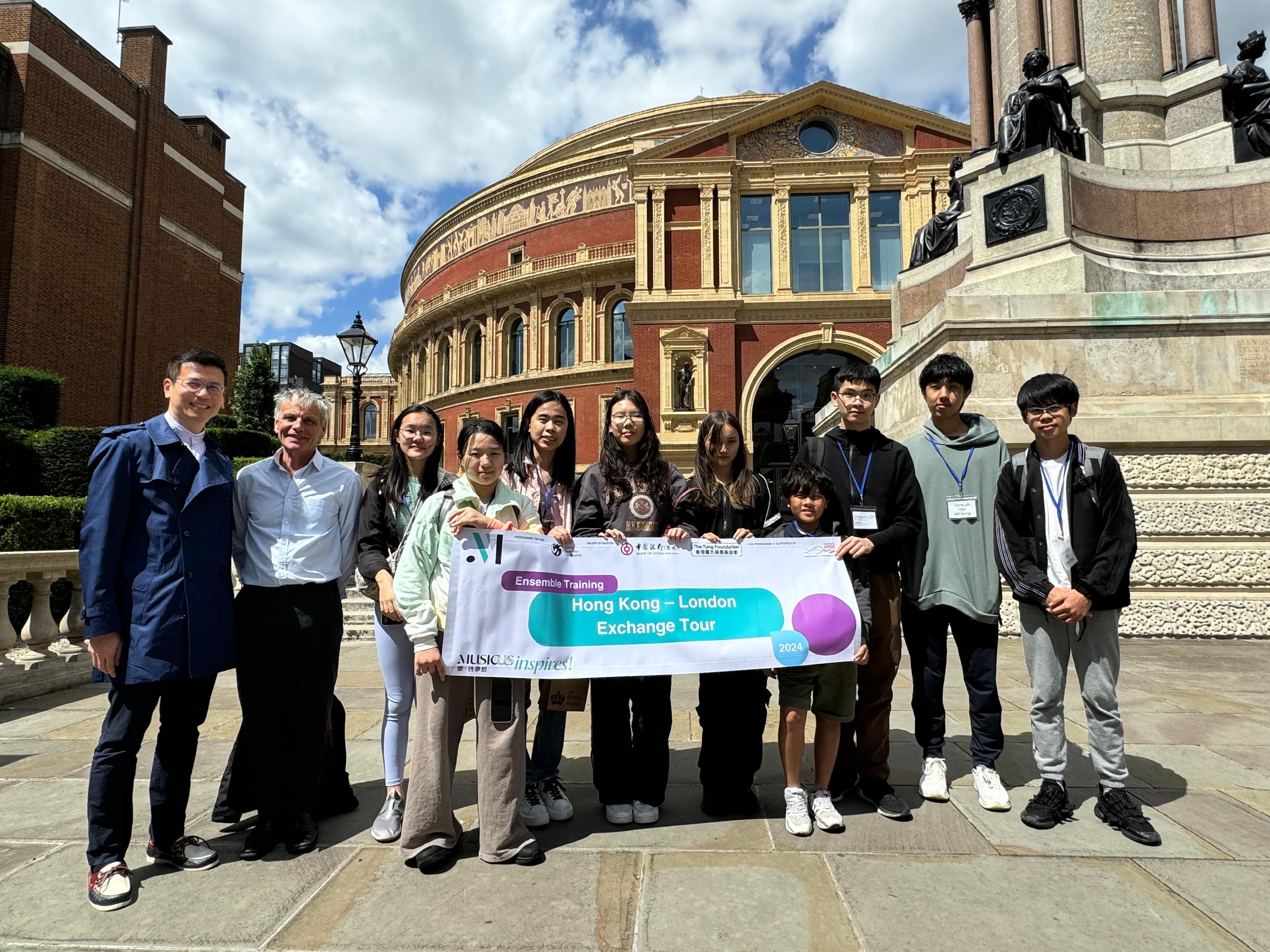 The Hong Kong Economic and Trade Office, London (London ETO) supports Musicus Society's cultural exchange tour in partnership with the English Chamber Orchestra (ECO) from July 3 to 9, 2024 (London time). Photo shows the Director-General of the London ETO, Mr Gilford Law (first left), a representative of the ECO, and nine Hong Kong students of the tour at the Royal Albert Hall in London.  