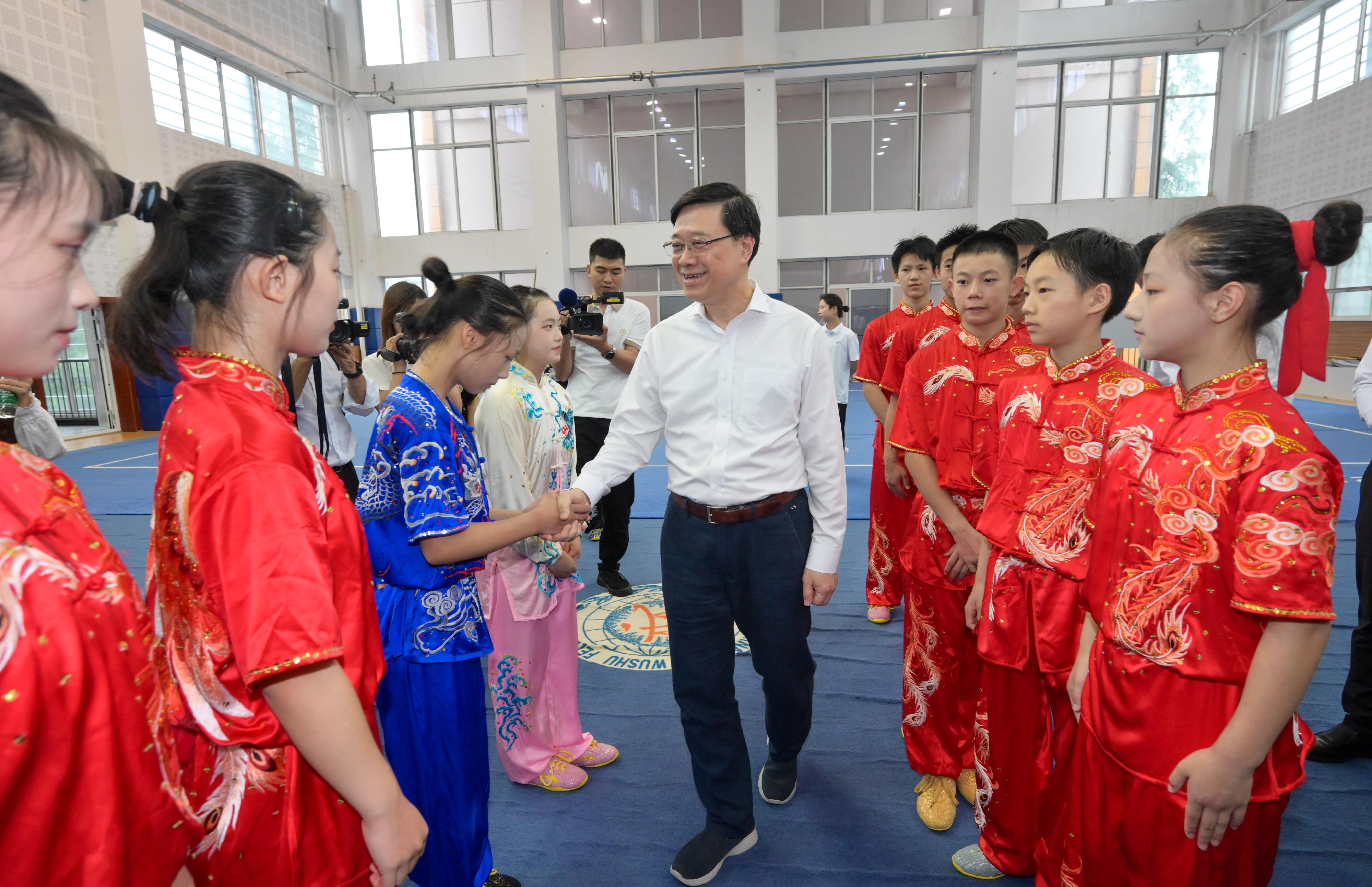 The Chief Executive, Mr John Lee, and his wife Mrs Janet Lee started their visit to Sichuan today (July 8). Photo shows Mr Lee (centre) visiting the Sichuan HKJC Olympic School and shaking hands with wushu students.