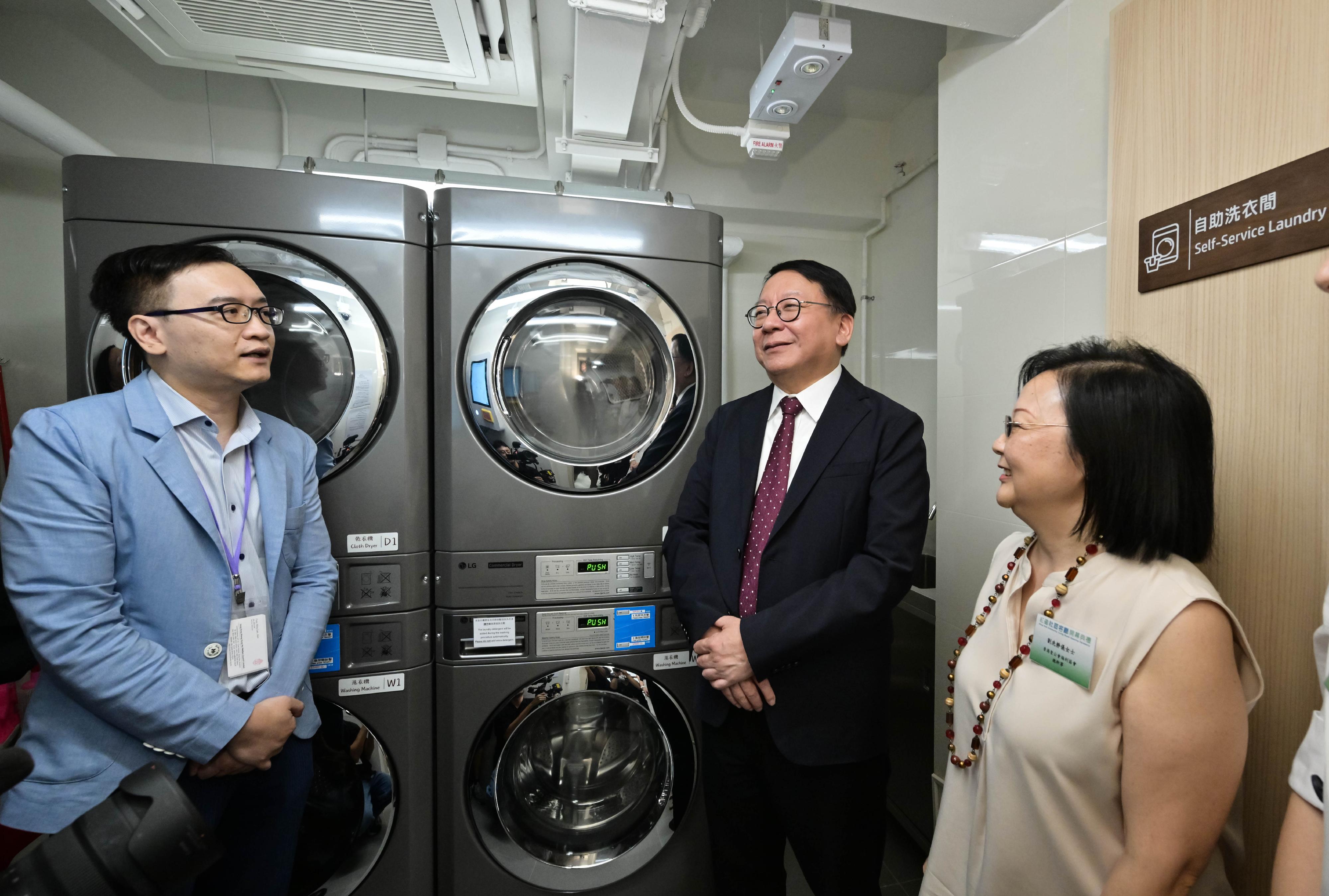陳國基（中）參觀自助洗衣設施，了解設施如何改善「劏房」戶的生活。