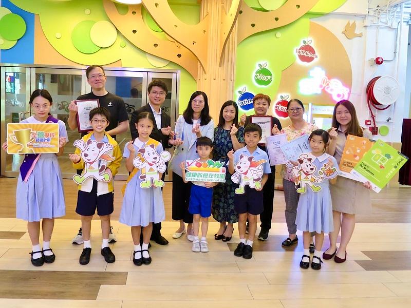 Representatives of the Department of Health (DH) visited schools attaining accreditation of the EatSmart School Accreditation Scheme in the 2023/24 school year and presented awards in June. Photo shows the Head of Health Promotion Branch (HPB) of the DH, Dr Leung Yiu-hong (back row, second left), along with other HPB representatives presenting the Award for Continuous Promotion of Healthy Eating at School to the Sha Tin Methodist Primary School, which attained the EatSmart School accreditation for the fifth consecutive time, during a school visit.