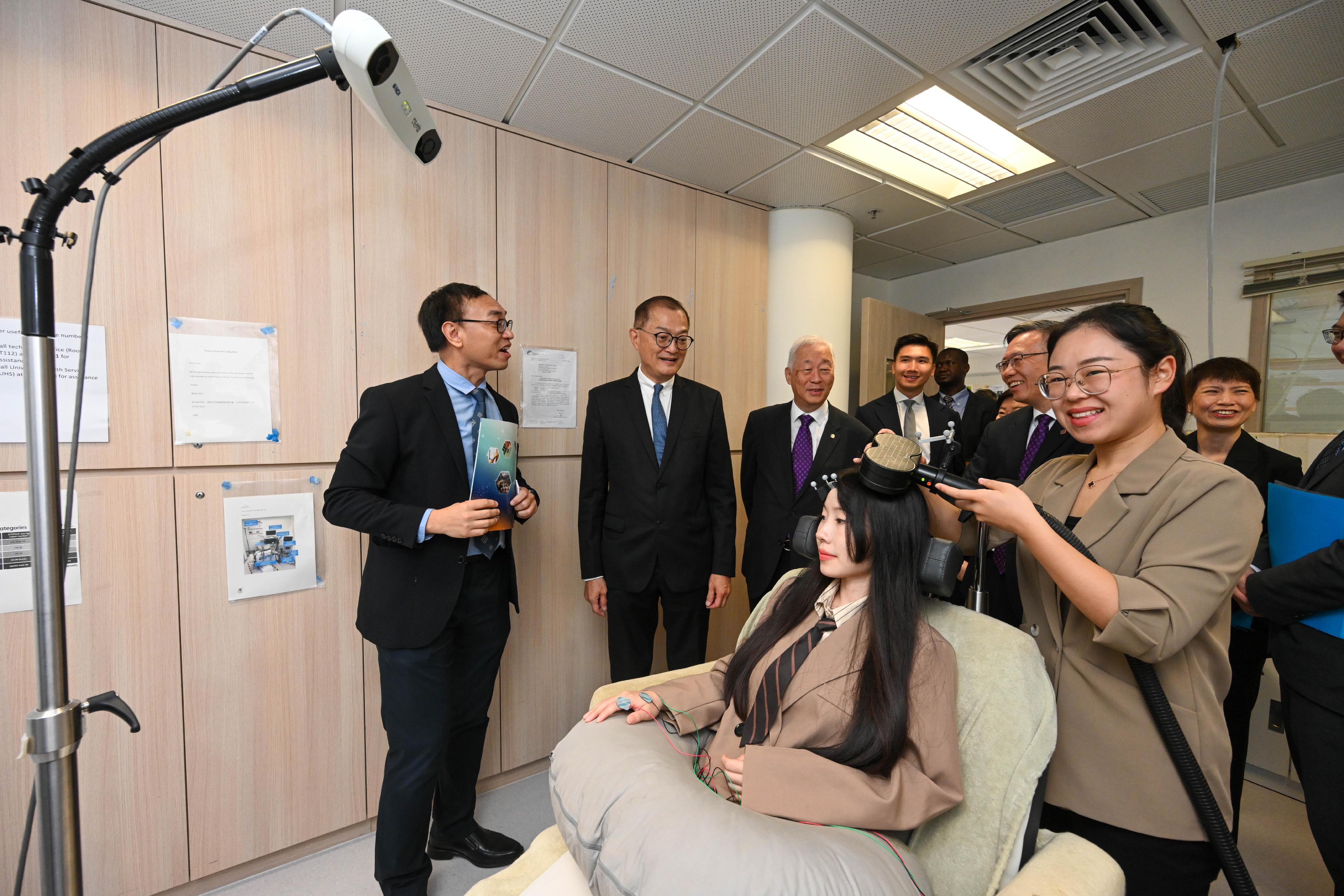 The Secretary for Health, Professor Lo Chung-mau (second left), visits the teaching facilities of the Department of Rehabilitation Sciences at the Hong Kong Polytechnic University (PolyU) in the company of the Deputy Chairman of PolyU Council, Dr Lawrence Li (third left), and ​the President of PolyU, Professor Teng Jinguang (fifth left), to learn about the functions of a rehabilitation device from the staff there today (July 22).