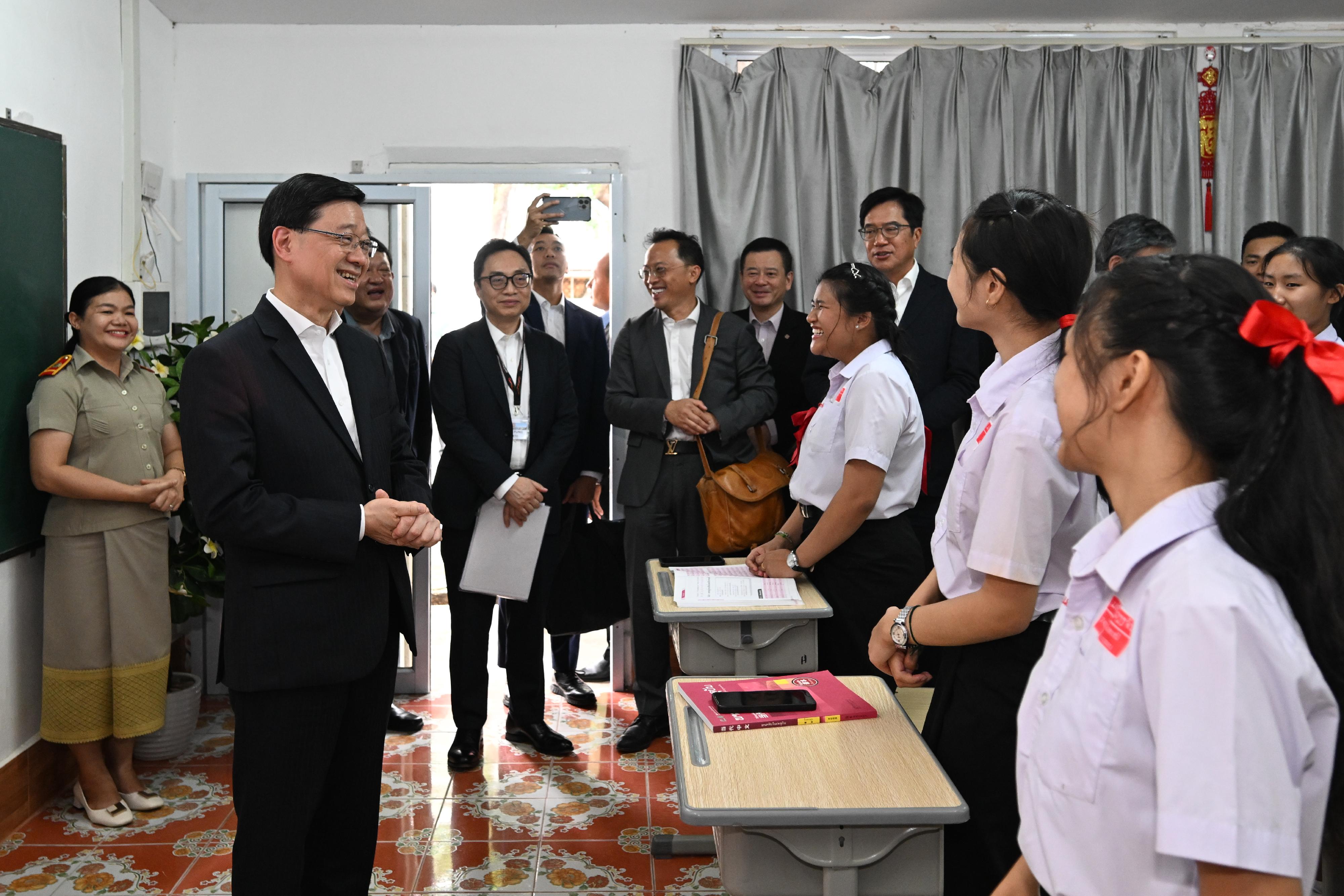 The Chief Executive, Mr John Lee, led a Hong Kong Special Administrative Region Government delegation to Laos and continued his visit programme today (July 29). Photo shows Mr Lee (second left) exchanging views with students at a secondary school at Laos.