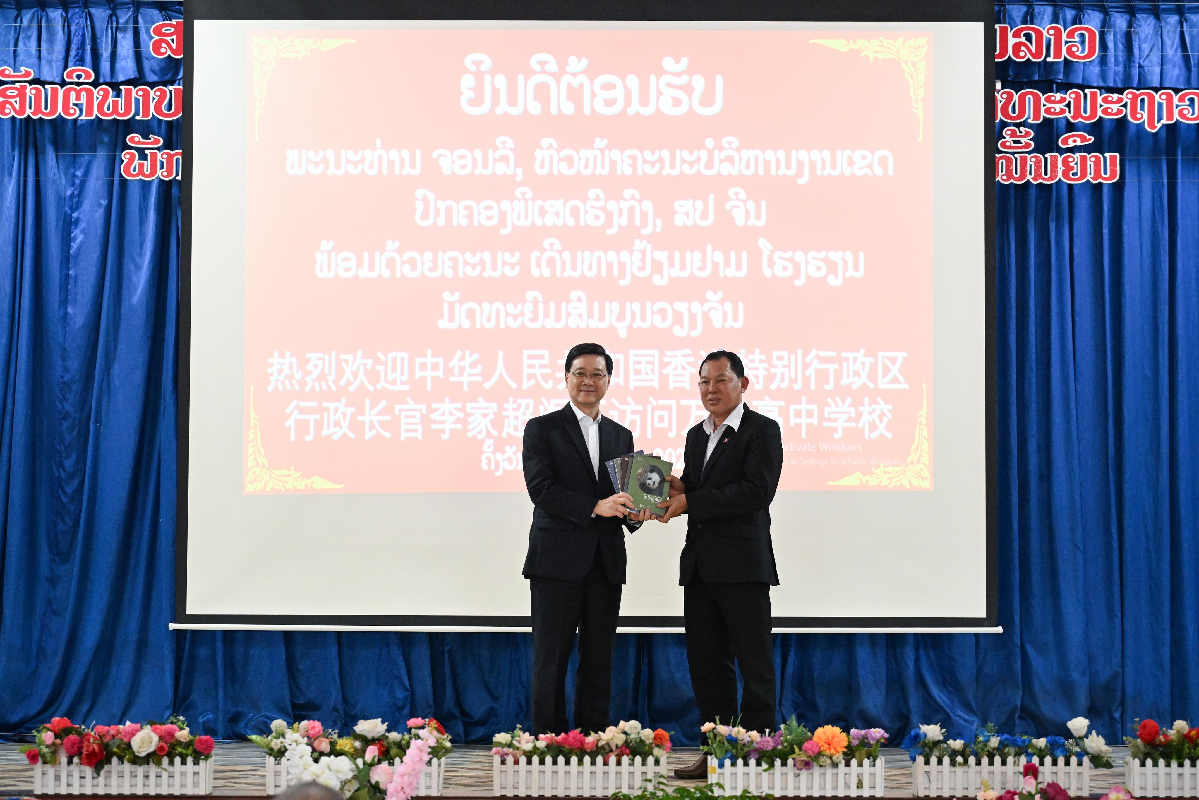 The Chief Executive, Mr John Lee, led a Hong Kong Special Administrative Region Government delegation to Laos and continued his visit programme today (July 29). Photo shows Mr Lee (left) presenting souvenir to the principal of a secondary school at Laos (right).