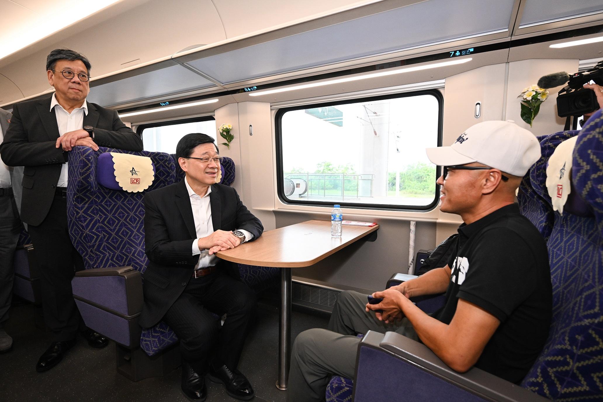 The Chief Executive, Mr John Lee, today (July 29) led a Hong Kong Special Administrative Region delegation to continue their visit in Vientiane, the capital of Laos. Photo shows Mr Lee (centre) and the Secretary for Commerce and Economic Development, Mr Algernon Yau (left), chatting with a passenger in the car compartment at the Vientiane Station of the China-Laos Railway.