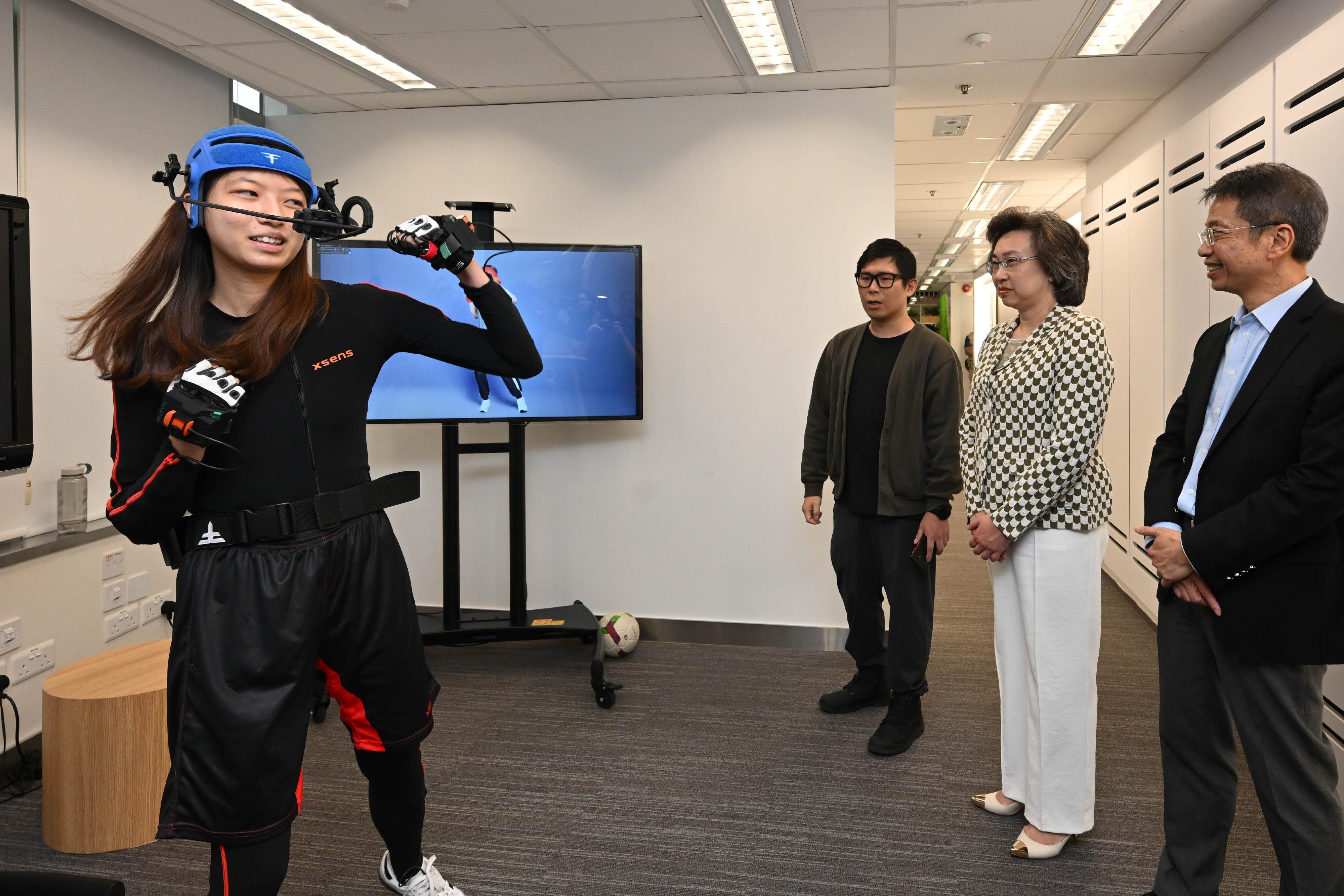 The Secretary for the Civil Service, Mrs Ingrid Yeung, today (July 30) visited the Artificial Intelligence Laboratory and the new studios of Radio Television Hong Kong (RTHK) in Kwun Tong to see the department's new directions in the use of technology in television production. Photo shows Mrs Yeung (second right) watching a demonstration by an intern of a motion capture system, which uses artificial intelligence (AI) to recognise different facial expressions and sensors to capture full body movements, and gloves to track finger movements, connected to an unreal engine with high-performance computing to produce images for RTHK Television's AI presenter, Aida. Looking on is the Permanent Secretary for the Civil Service, Mr Clement Leung (first right).