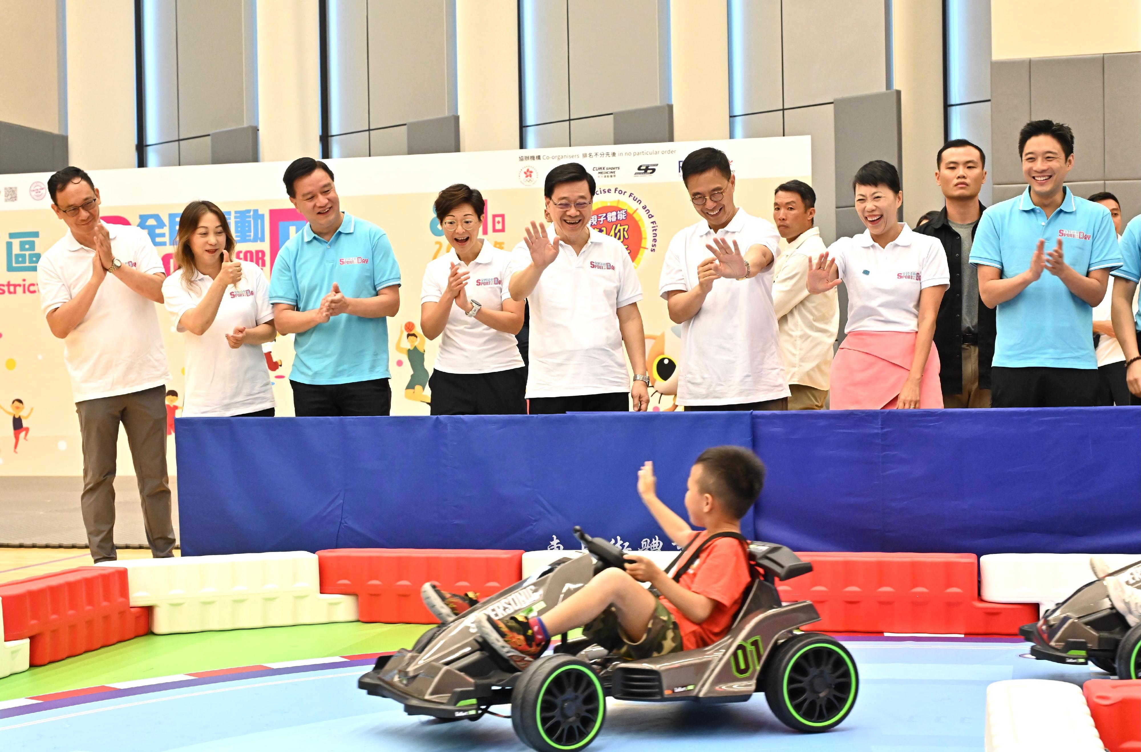 The Chief Executive, Mr John Lee, attended the Sport For All Day 2024 held by the Leisure and Cultural Services Department this afternoon (August 4) at the Tung Cheong Street Sports Centre, Tai Po, to promote the message of regular exercising for health. Photo shows Mr Lee (fourth right ); the Secretary for Culture, Sports and Tourism, Mr Kevin Yeung (third right); and other guests watching an e-racing for kids.