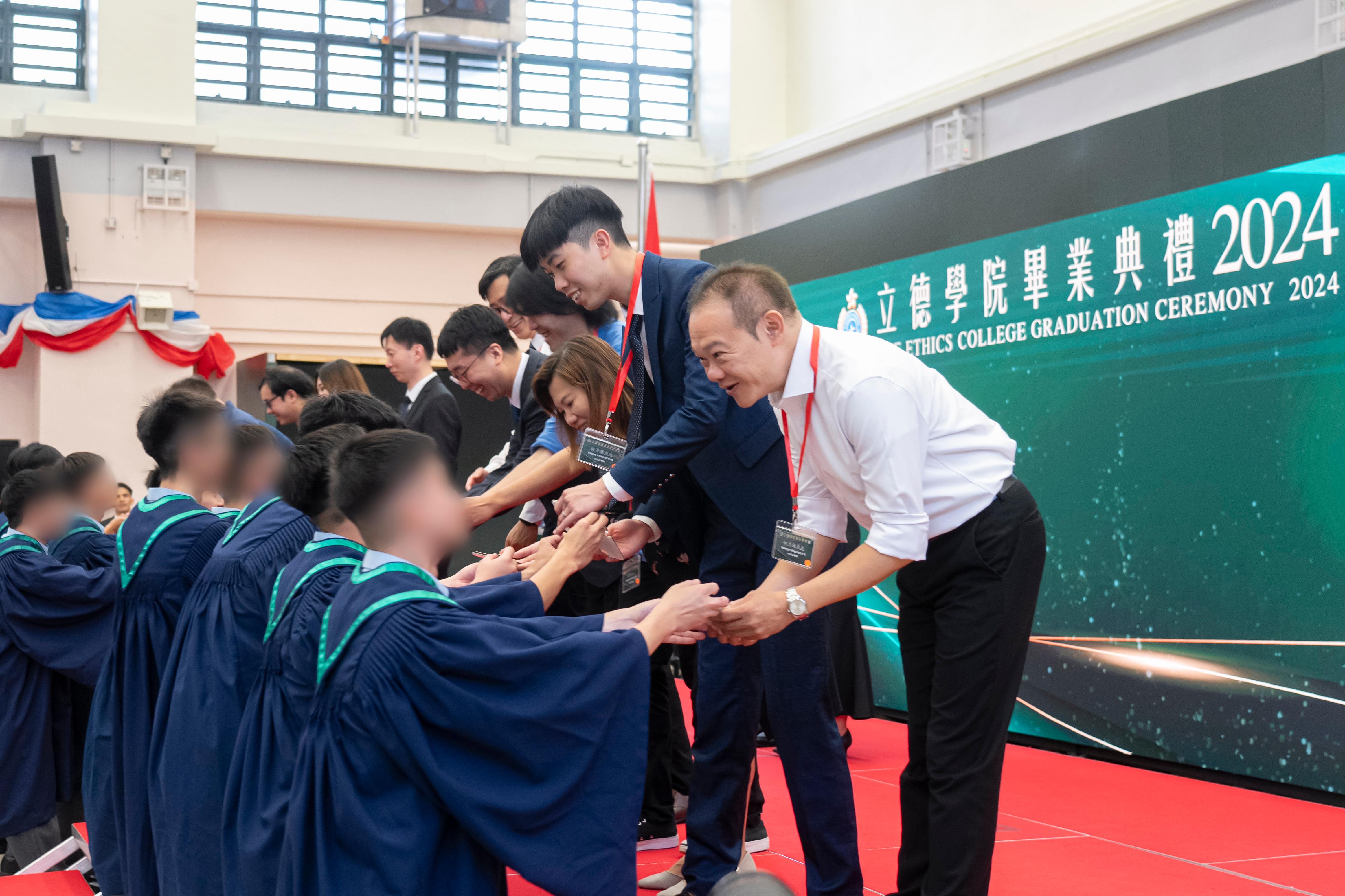 惩教署今日（八月八日）在白沙湾惩教所举行「立德学院」首届毕业典礼，颁发毕业证书予修毕应用教育文凭的在囚人士。图示在囚人士致送纪念品给授课老师表示谢意。