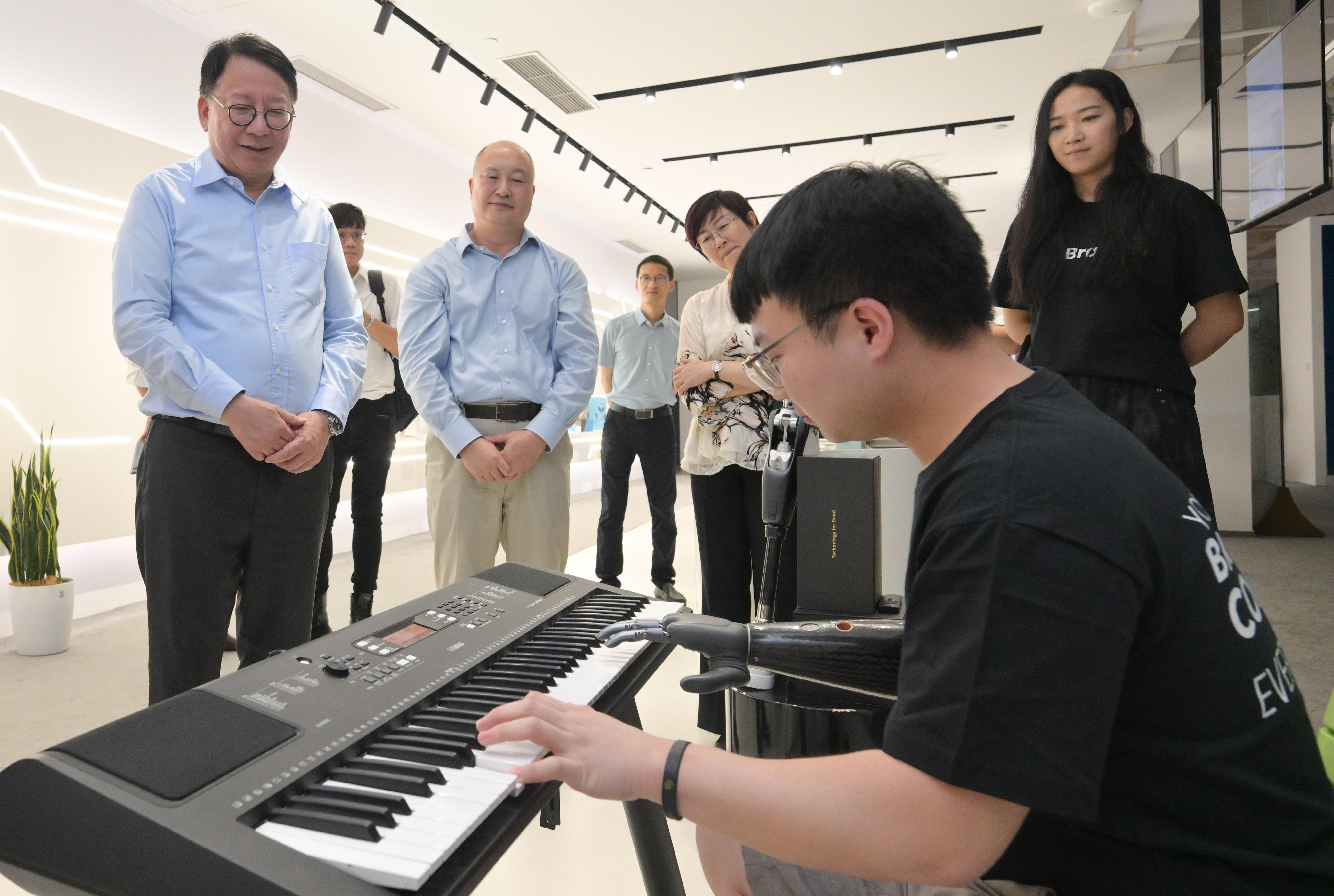 The Chief Secretary for Administration, Mr Chan Kwok-ki, continued his visit to Hangzhou today (August 13). Photo shows Mr Chan (first left) visiting a high-technology start-up, BrainCo, and watching a demonstration of a smart prosthesis playing the piano.