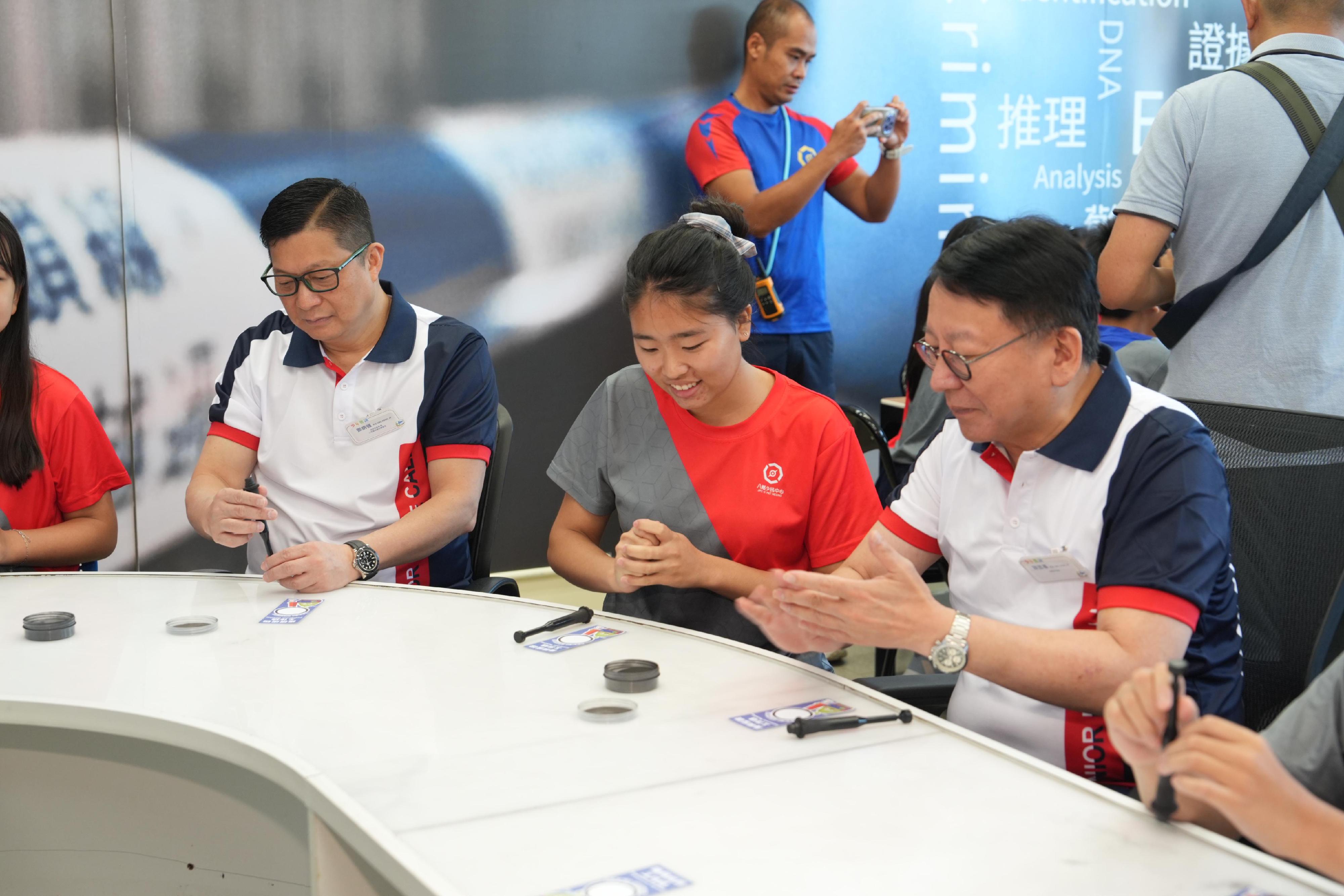 The Opening Ceremony of Junior Police Call Summer Camp 2024 was held today (August 17). Photo shows the Chief Secretary for Administration, Mr Chan Kwok-ki (first right) and the Secretary for Security cum Junior Police Call (JPC) Honorary Chief President, Mr Tang Ping-keung (first left) taking part in a fingerprint identification workshop with the JPC members.