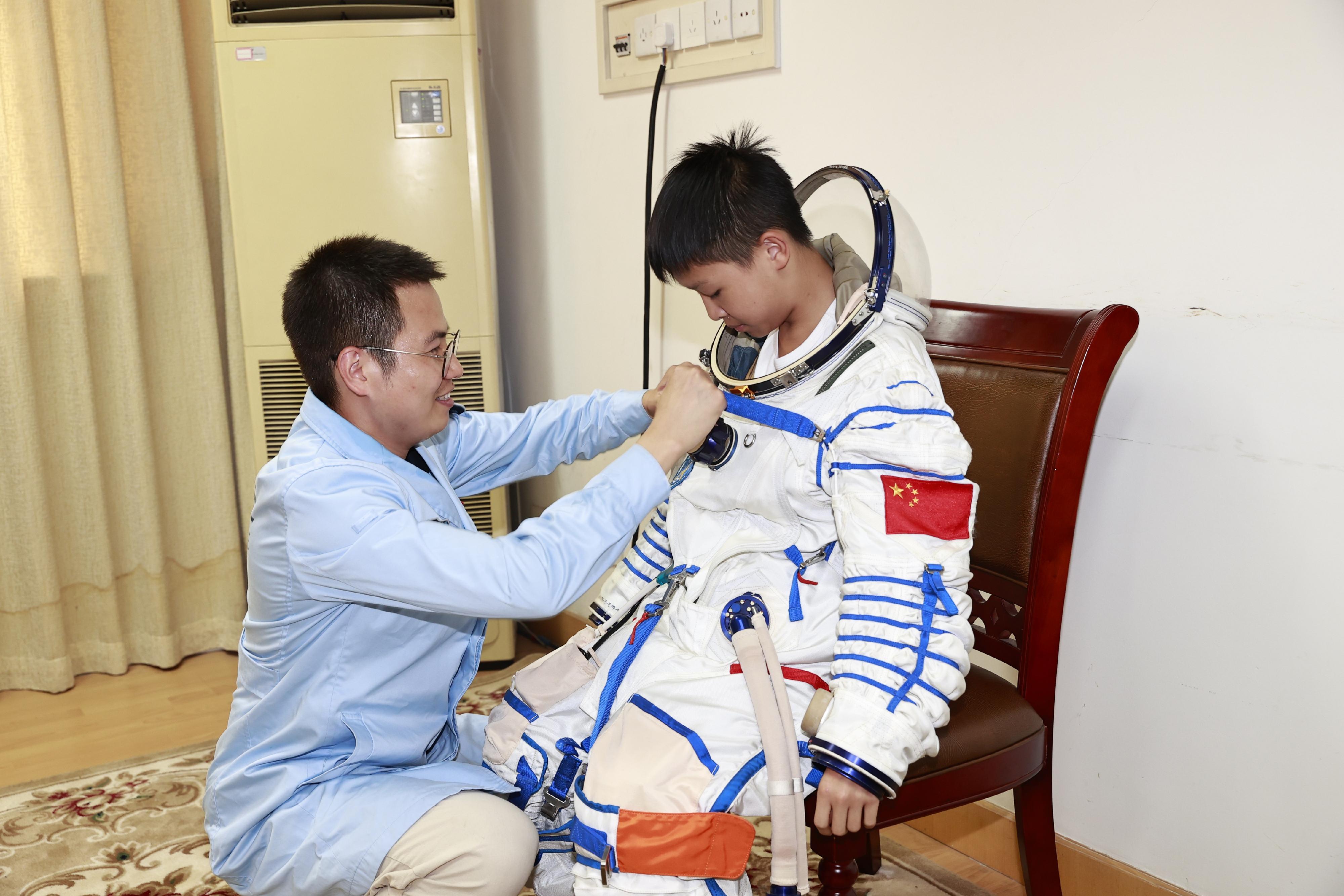 Students of the Young Astronaut Training Camp 2024 have just completed their nine-day training camp in Beijing, Wenchang of Hainan Province and Jiuquan. They were presented with certificates at a sharing session held at the Hong Kong Space Museum today (August 20). Photo shows a student trying the donning and doffing of a spacesuit at the Beijing Aerospace City.