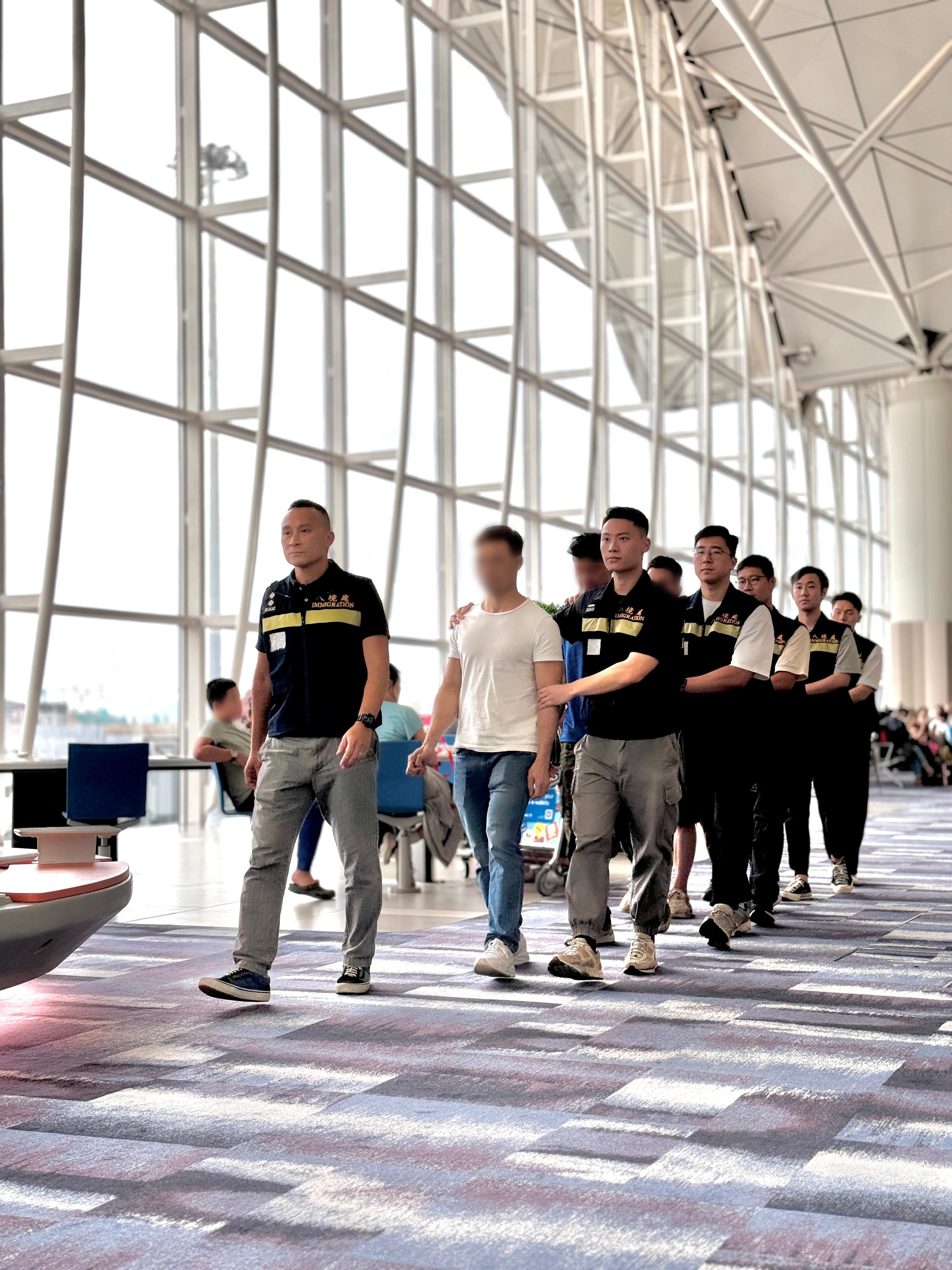 The Immigration Department (ImmD) carried out a repatriation operation today (August 21).  A total of 22 Vietnamese illegal immigrants were repatriated to Vietnam.  Photo shows removees being escorted by ImmD officers to depart from Hong Kong.