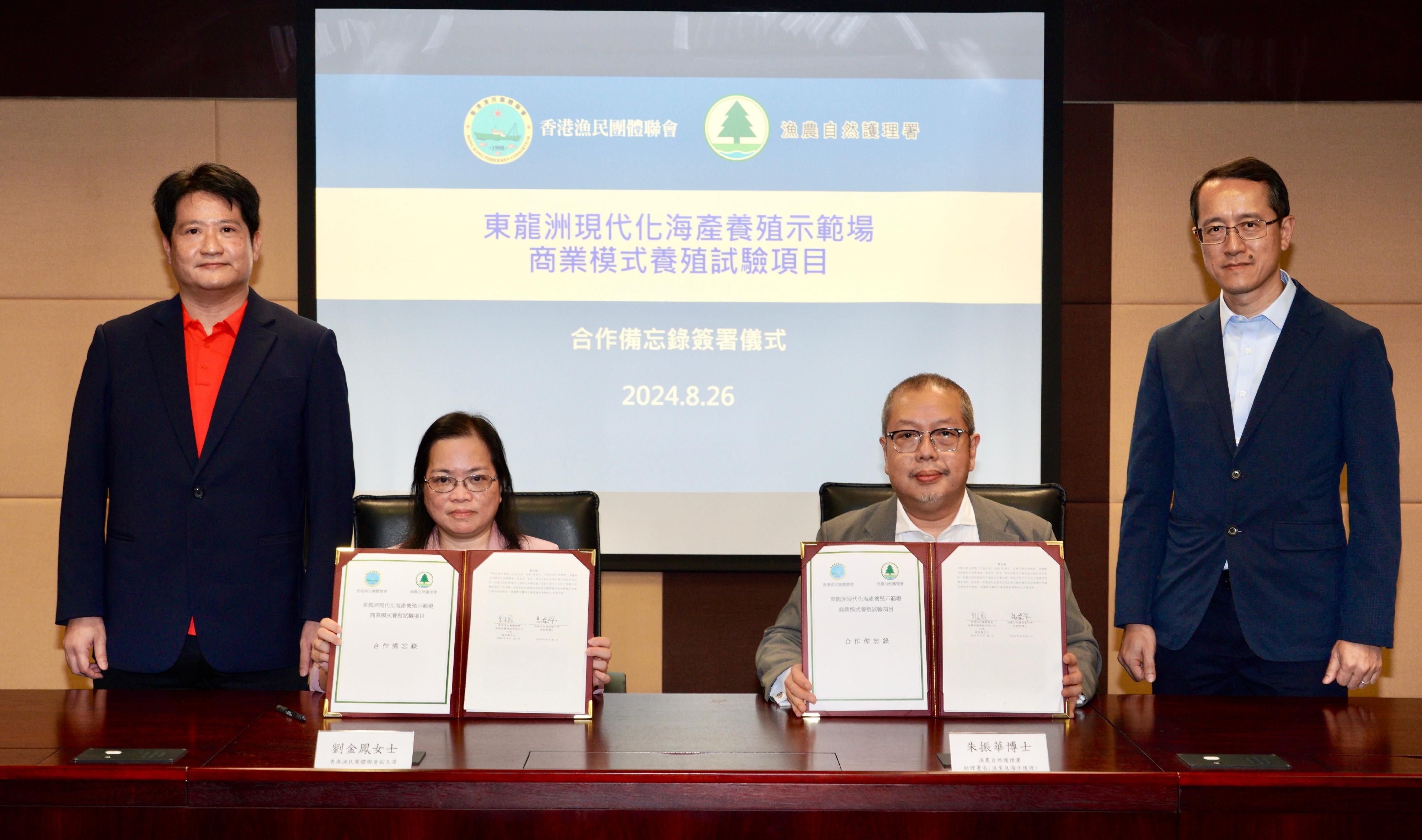 渔农自然护理署（渔护署）今日（八月二十六日）与香港渔民团体联会（渔联）就东龙洲鱼类养殖区现代化海产养殖示范场开展商业模式养殖试验项目签订合作备忘录。图示渔护署助理署长（渔业及海洋护理）朱振华博士（右二）和渔民团体联会副主席刘金凤（左二）在渔护署副署长黎存志（右一）及渔联执行会长陈博智（左一）的见证下签订合作备忘录后合照。
