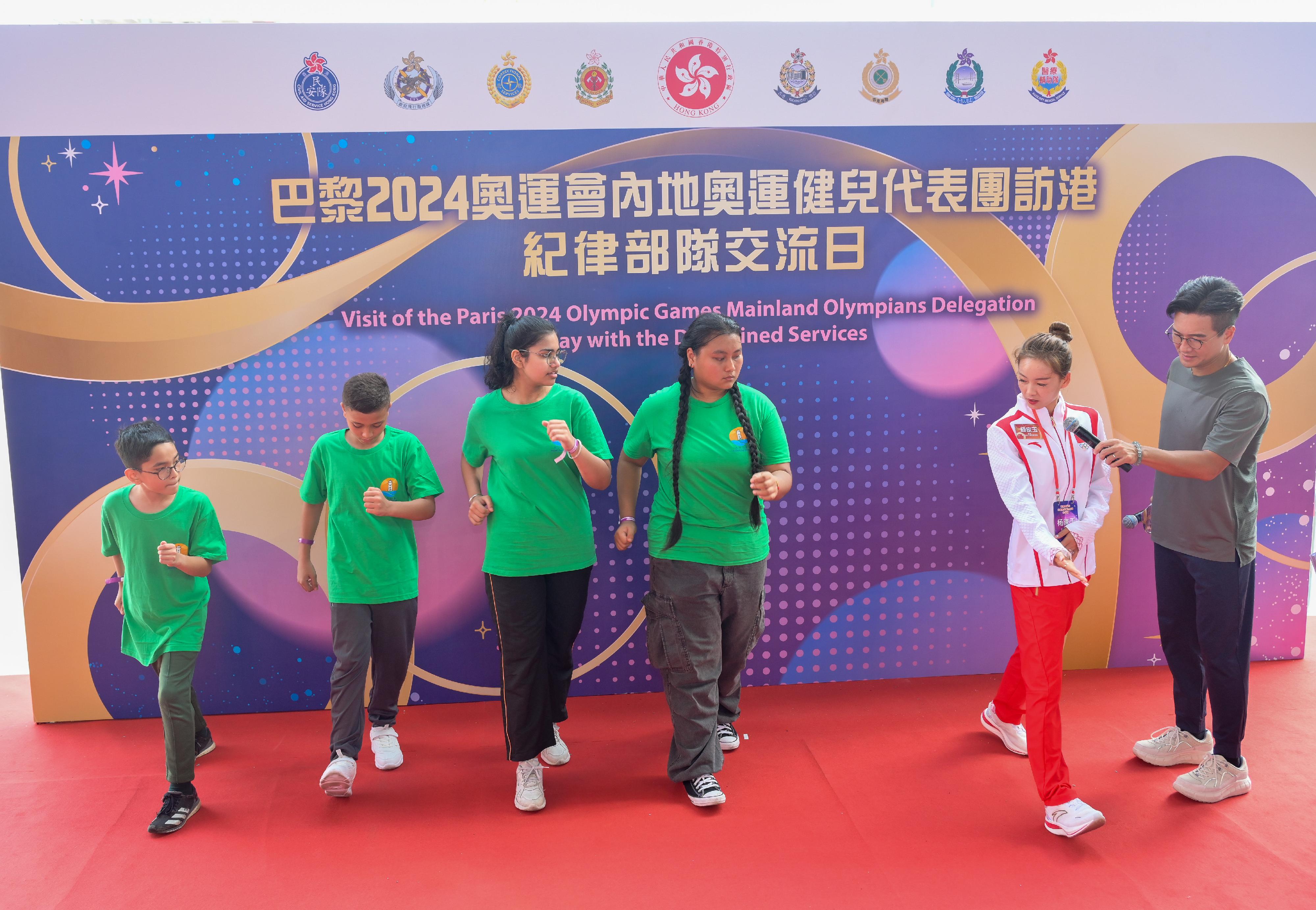 二○二四年巴黎奥运会内地奥运健儿代表团昨日（八月二十九日）起访问香港三日，当中29人包括22名运动员及三名教练今日（八月三十日）上午在消防及救护学院与纪律部队和辅助部队人员，及其辖下青少年制服团队队员交流会面，分享他们的得奖喜悦，并进行示范表演。图示内地田径运动员杨家玉（右二）示范田径的技巧。