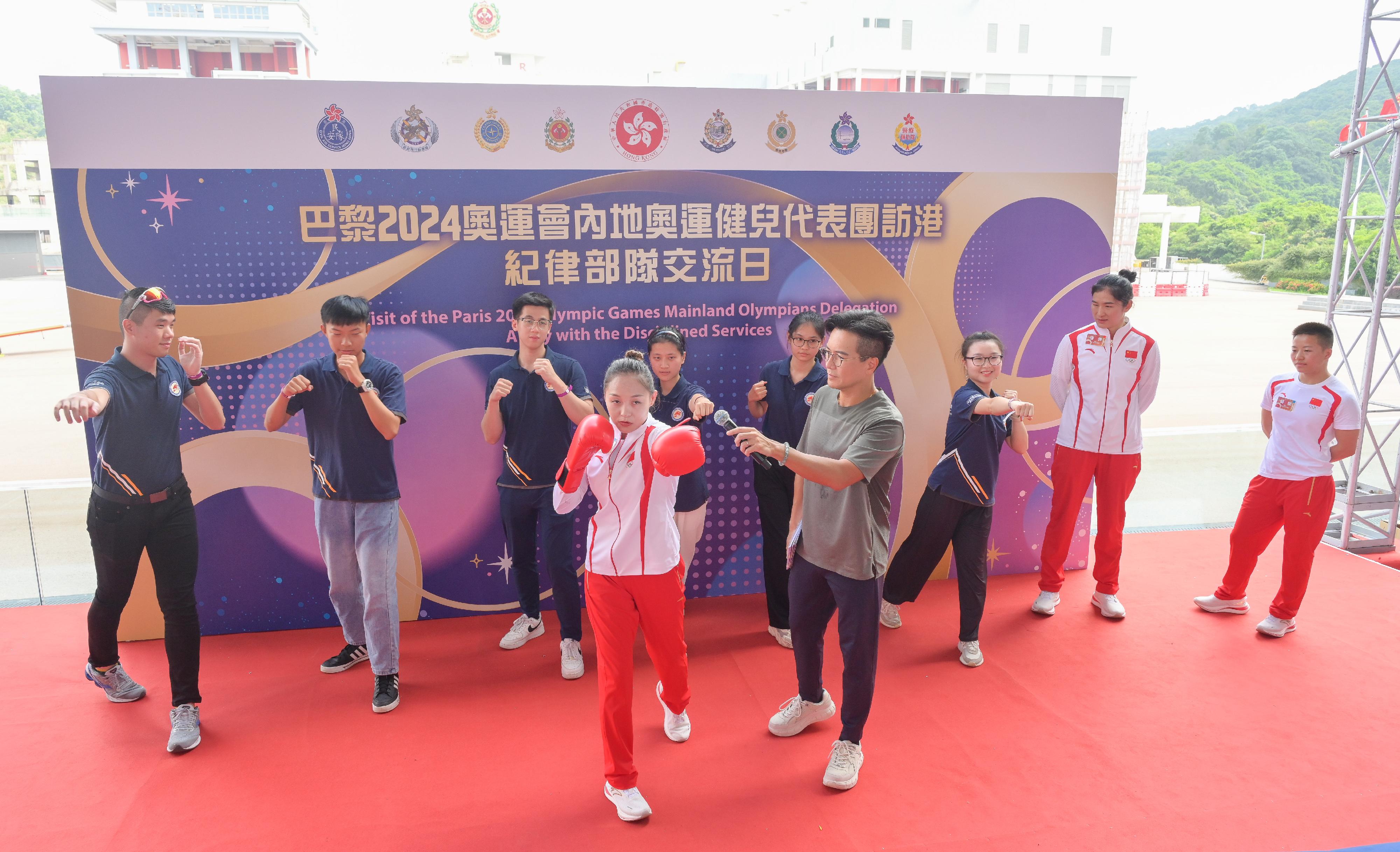 二○二四年巴黎奥运会内地奥运健儿代表团昨日（八月二十九日）起访问香港三日，当中29人包括22名运动员及三名教练今日（八月三十日）上午在消防及救护学院与纪律部队和辅助部队人员，及其辖下青少年制服团队队员交流会面，分享他们的得奖喜悦，并进行示范表演。图示内地拳击运动员吴愉（右一）、常园（左四）及李倩（右二）示范拳击的技巧。