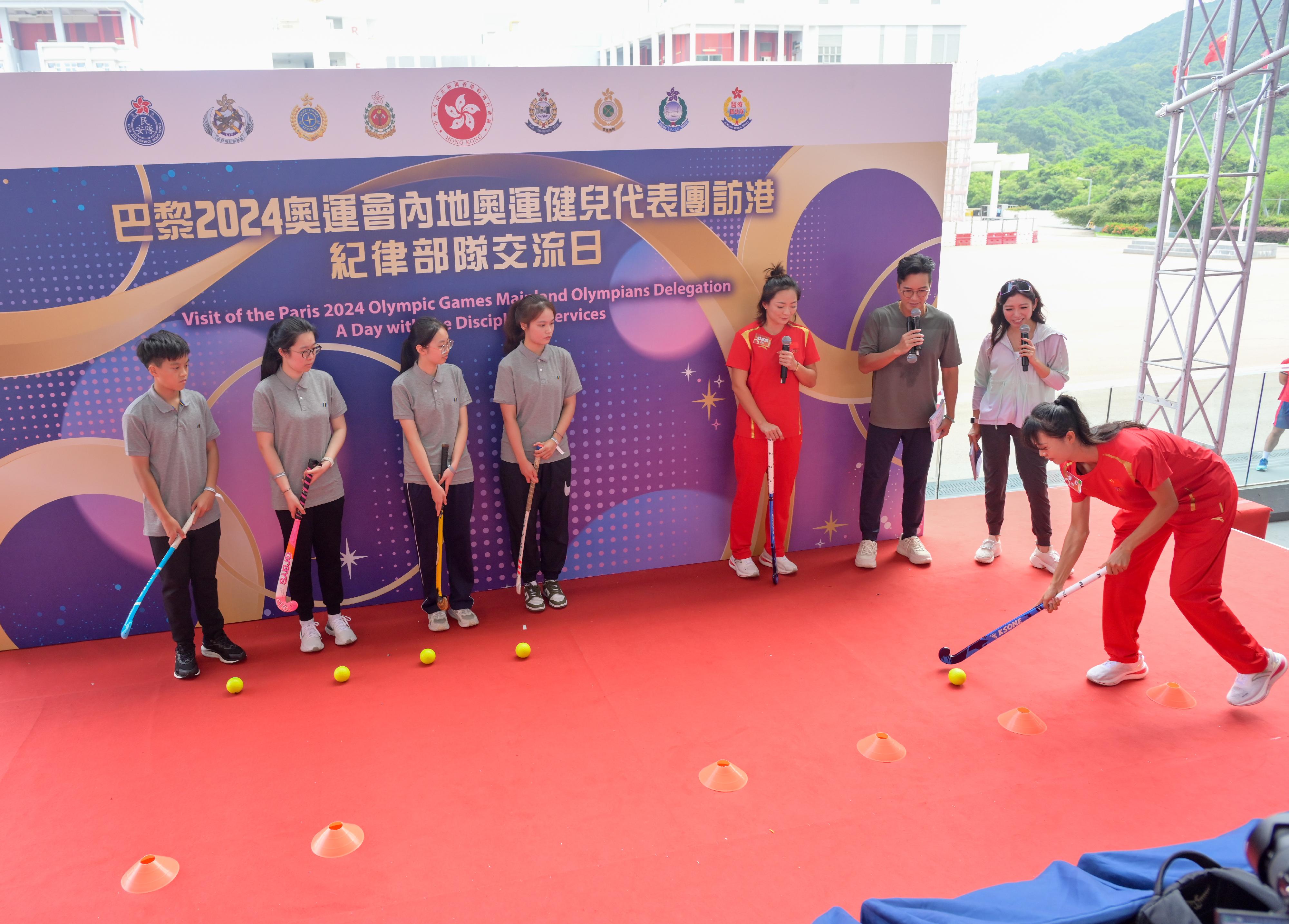 二○二四年巴黎奥运会内地奥运健儿代表团昨日（八月二十九日）起访问香港三日，当中29人包括22名运动员及三名教练今日（八月三十日）上午在消防及救护学院与纪律部队和辅助部队人员，及其辖下青少年制服团队队员交流会面，分享他们的得奖喜悦，并进行示范表演。图示内地曲棍球运动员欧紫霞（右四）及李红（右一）示范曲棍球的技巧。