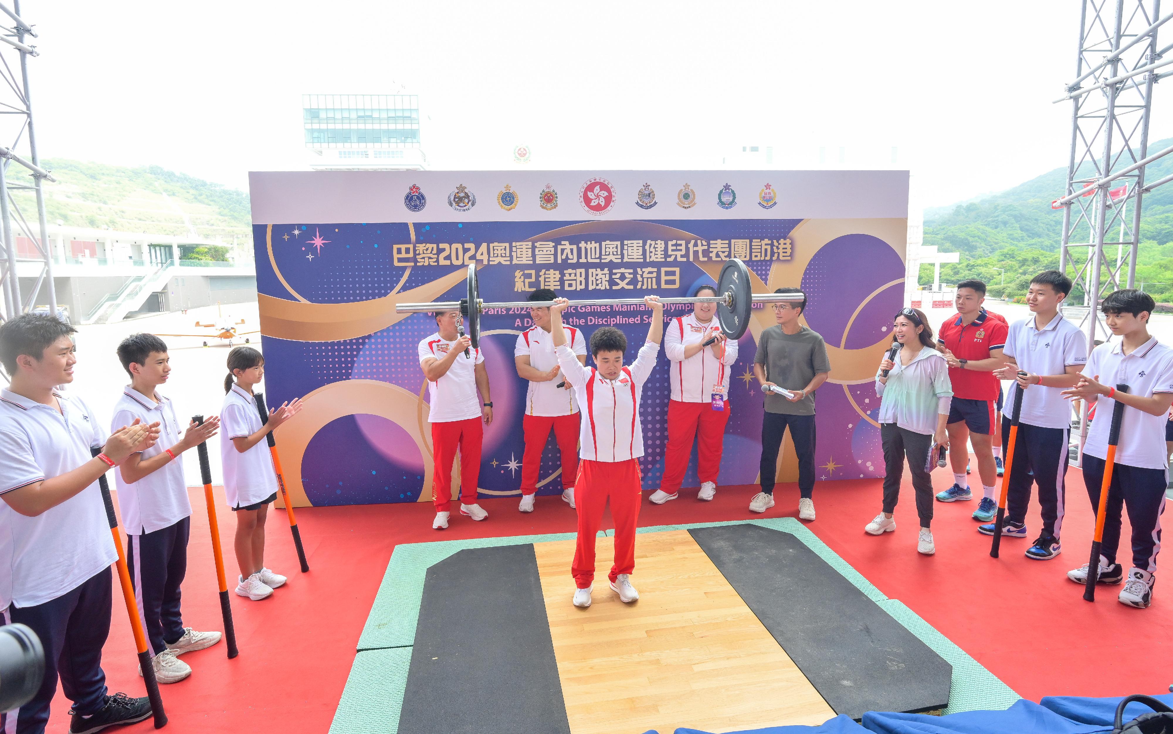 二○二四年巴黎奥运会内地奥运健儿代表团昨日（八月二十九日）起访问香港三日，当中29人包括22名运动员及三名教练今日（八月三十日）上午在消防及救护学院与纪律部队和辅助部队人员，及其辖下青少年制服团队队员交流会面，分享他们的得奖喜悦，并进行示范表演。图示内地举重运动员侯志慧（左六）、李雯雯（右六）及刘焕华（左五）示范举重的技巧。