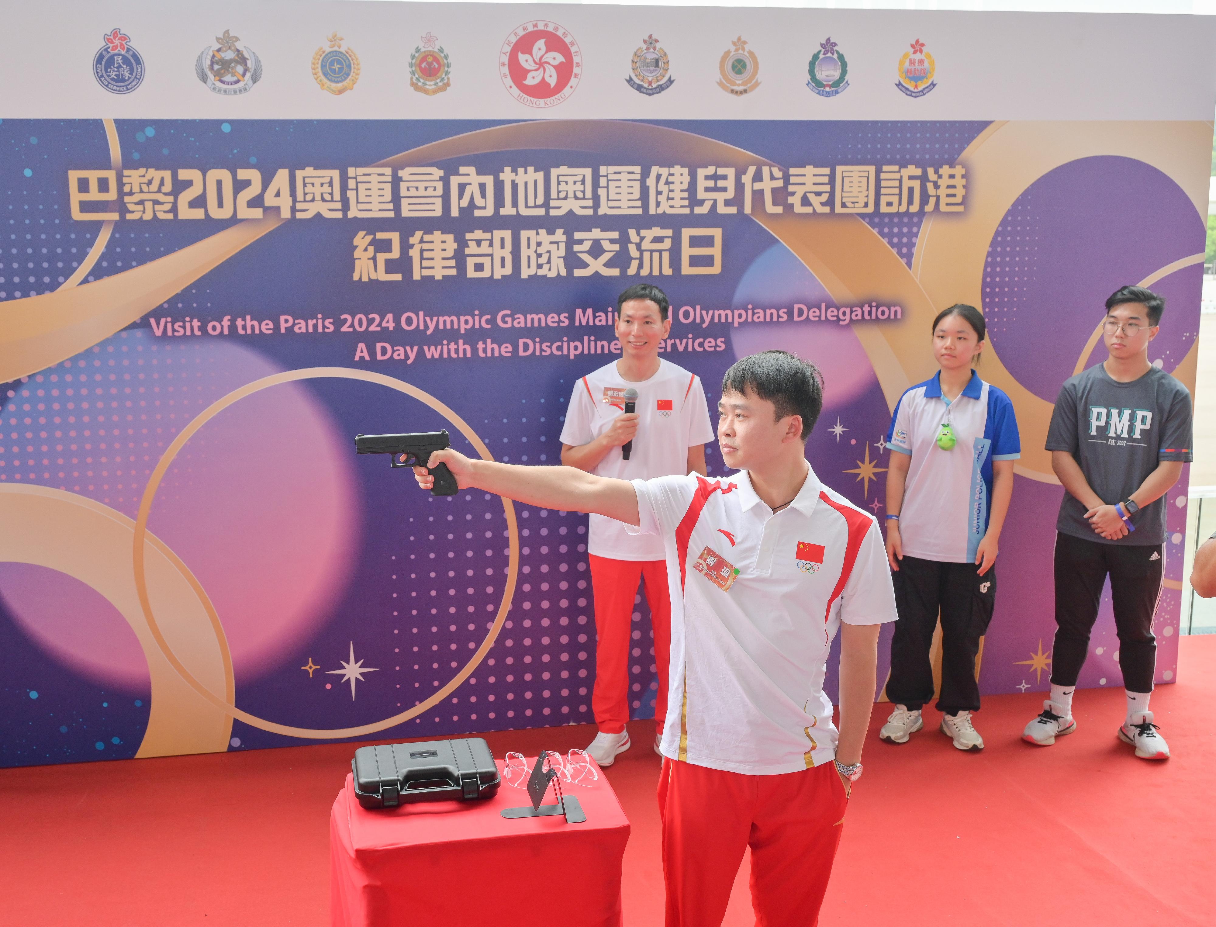 The delegation of the 2024 Paris Olympic Games Mainland Olympians arrived in Hong Kong yesterday (August 29) for a three-day visit. Twenty-nine people, including 22 athletes and three coaches, from the delegation met with members of the disciplined services and auxiliary services as well as their youth uniformed groups to share in the joy of the Olympians' achievements and give sports demonstrations at the Fire and Ambulance Services Academy this morning (August 30). Photo shows Mainland shooting athlete Xie Yu (second left) demonstrating shooting techniques.
