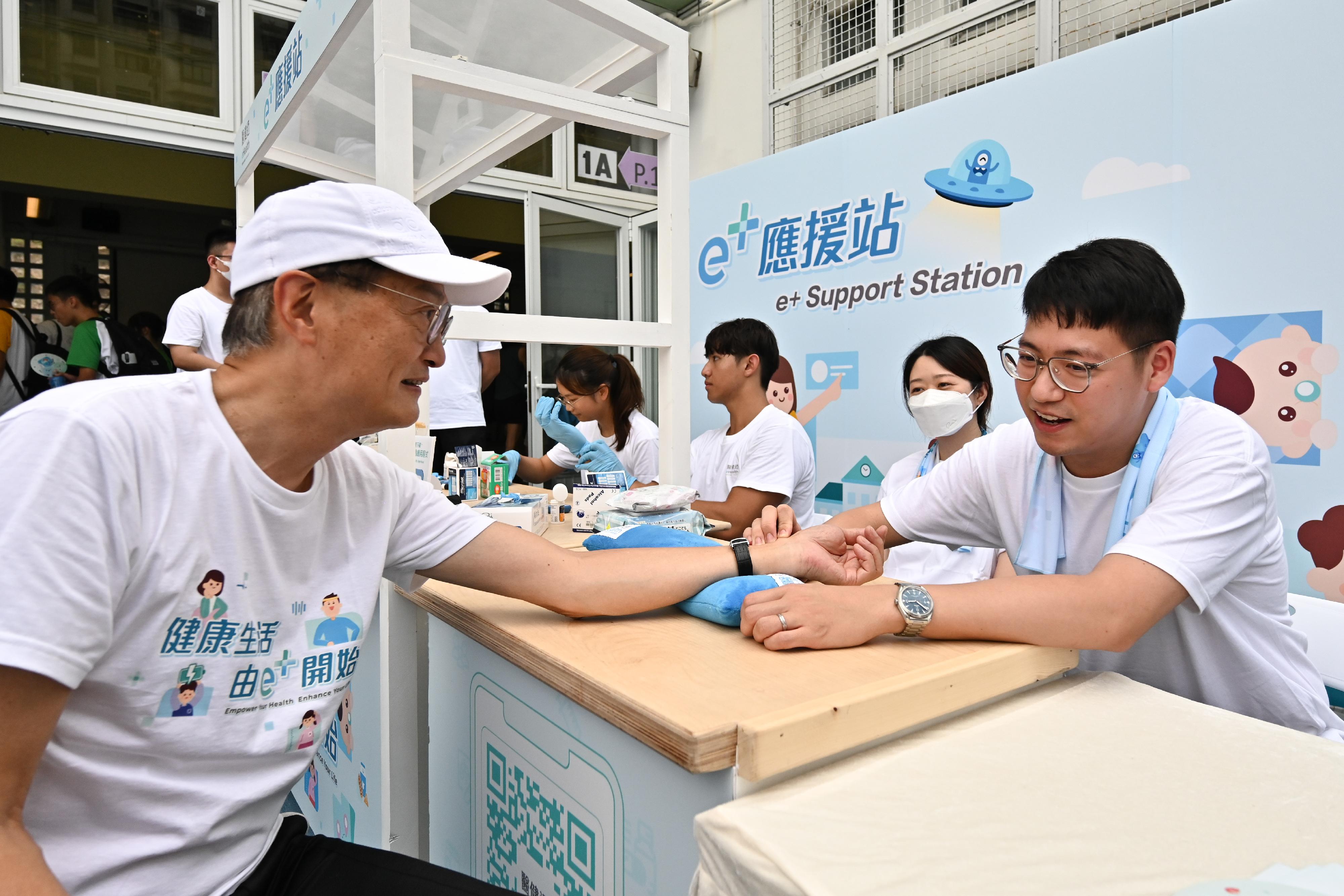 医务卫生局（医卫局）今日（九月十四日）在医健通首个健康挑战——「e+去公园」游戏启动礼上设置「e+应援站」，鼓励参加者登记成为医健通用户和加强管理自己的健康状况。图示医卫局局长卢宠茂教授（左）亲身体验应援站提供的中医健康谘询服务。