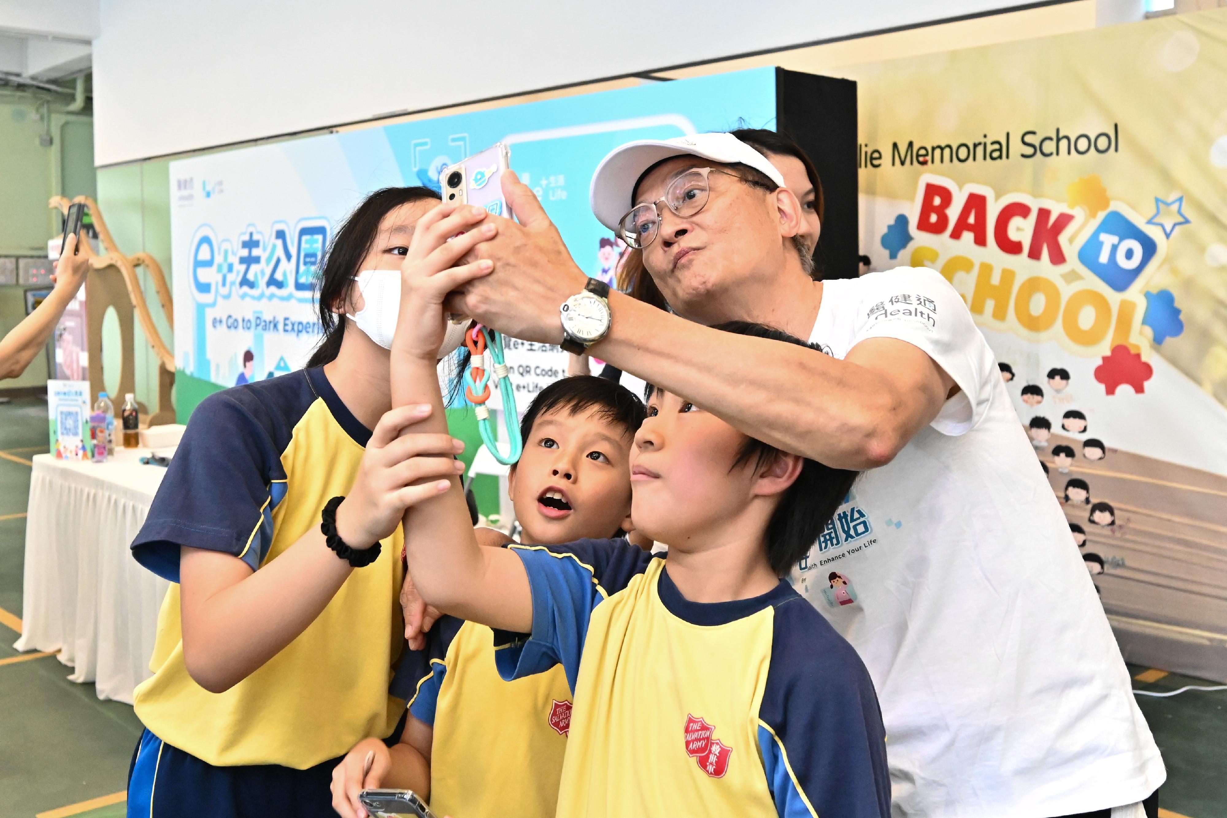 The Secretary for Health, Professor Lo Chung-mau, officiated at the launch ceremony of the first health challenge of eHealth, the "e+ Go to Park" game, today (September 14). Photo shows Professor Lo (first right) enjoying playing the game with students to capture virtual characters to replenish "sports energy".