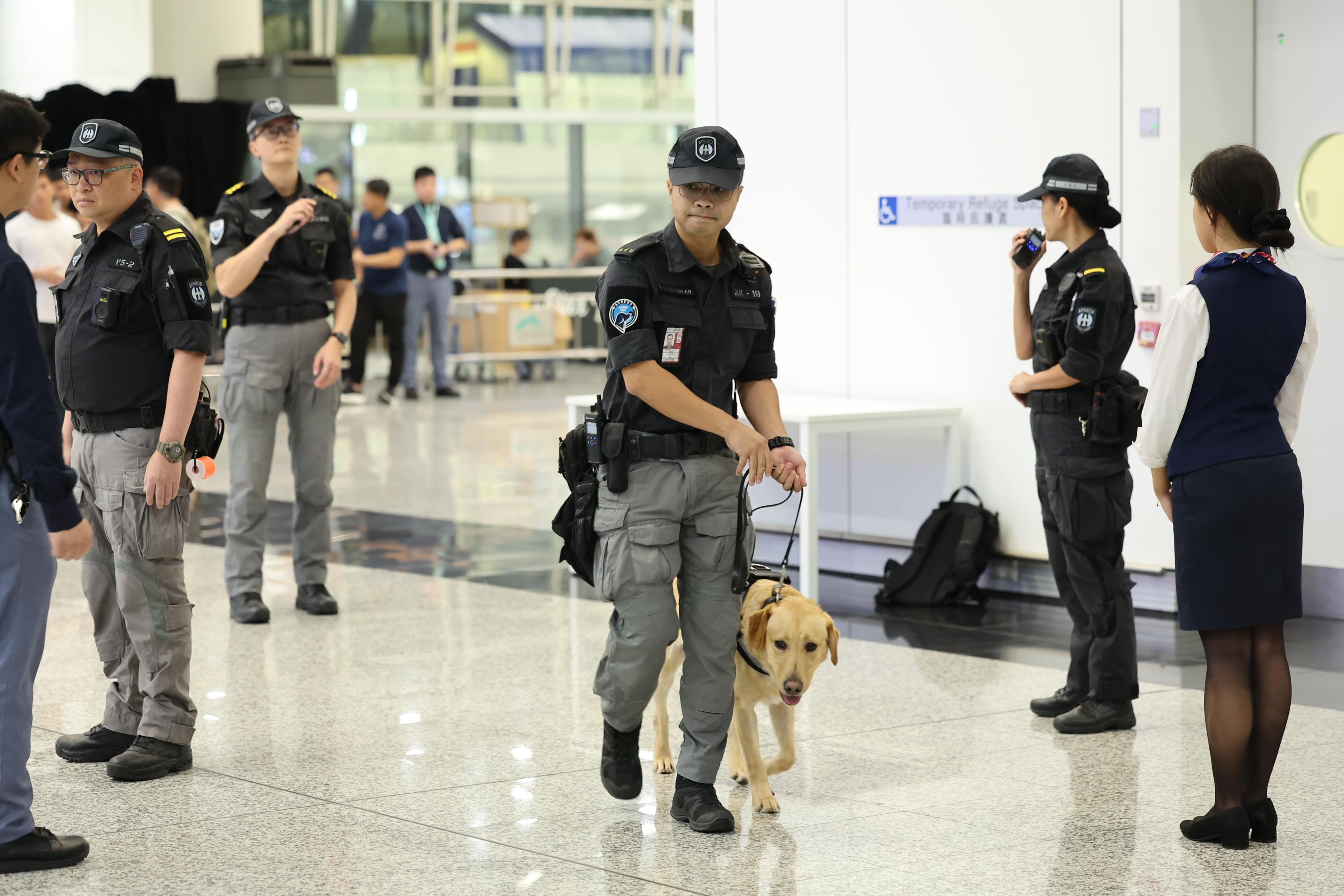 警方网络安全及科技罪案调查科今日（九月二十一日）与国际刑警组织及澳门司法警察局联合举办代号为「战风」的「网络及实体反恐联合演练2024」。图示机场保安有限公司机场保安犬只行动小组人员及搜索犬进行搜查工作。