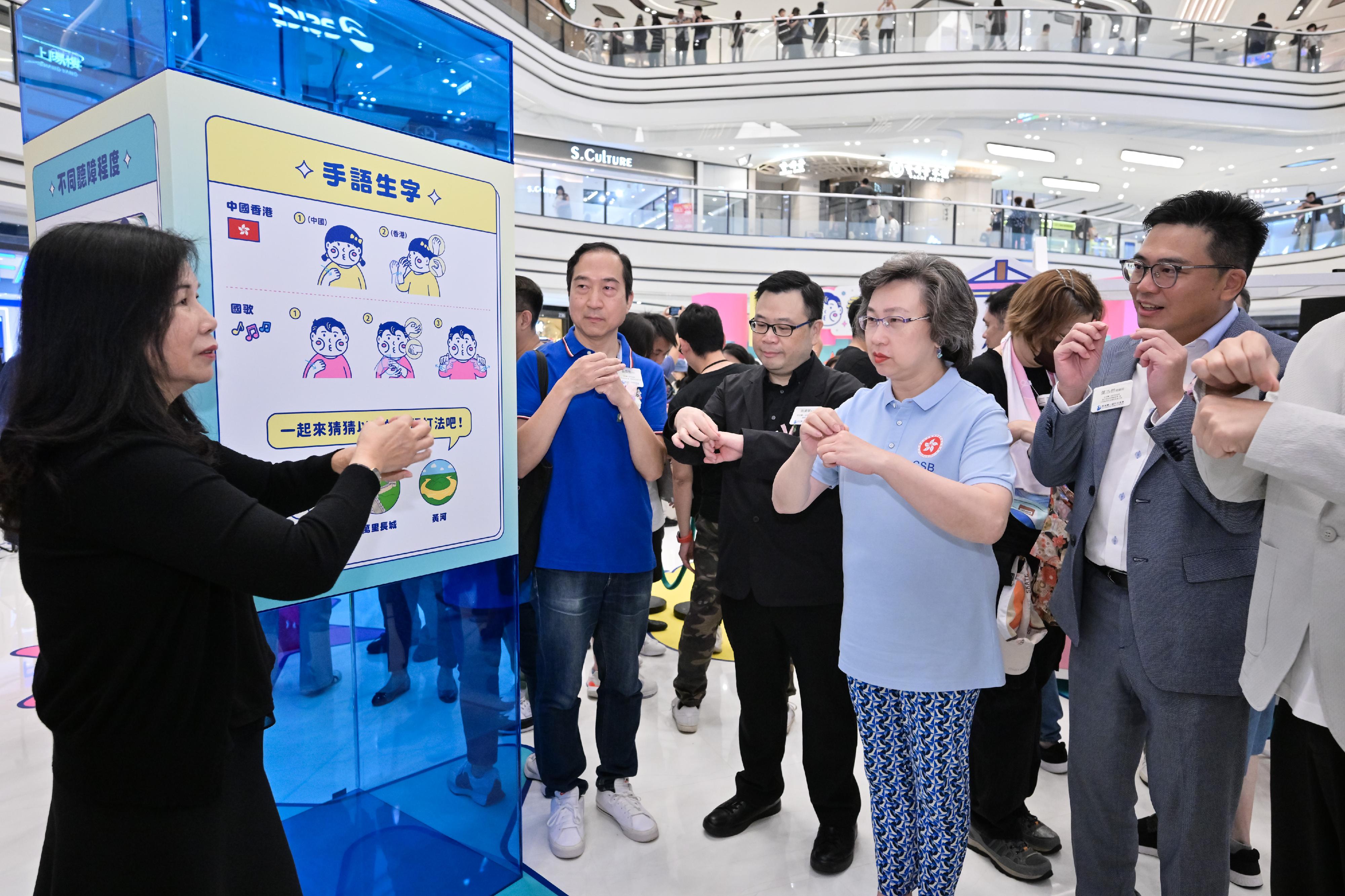 The Civil Service Bureau's Volunteer Team today (September 22) helped the Hong Kong Society for the Deaf to organise "Hong Kong Sign Language Day 2024" games at a shopping mall in Tai Wai, where members of the public could learn sign language and play games to encourage them to communicate more with the hearing impaired. Photo shows the Secretary for Civil Service, Mrs Ingrid Yeung (second right), learning simple sign-language phrases like "Hong Kong, China", "National Anthem" and "panda" under the guidance of a sign-language teacher.