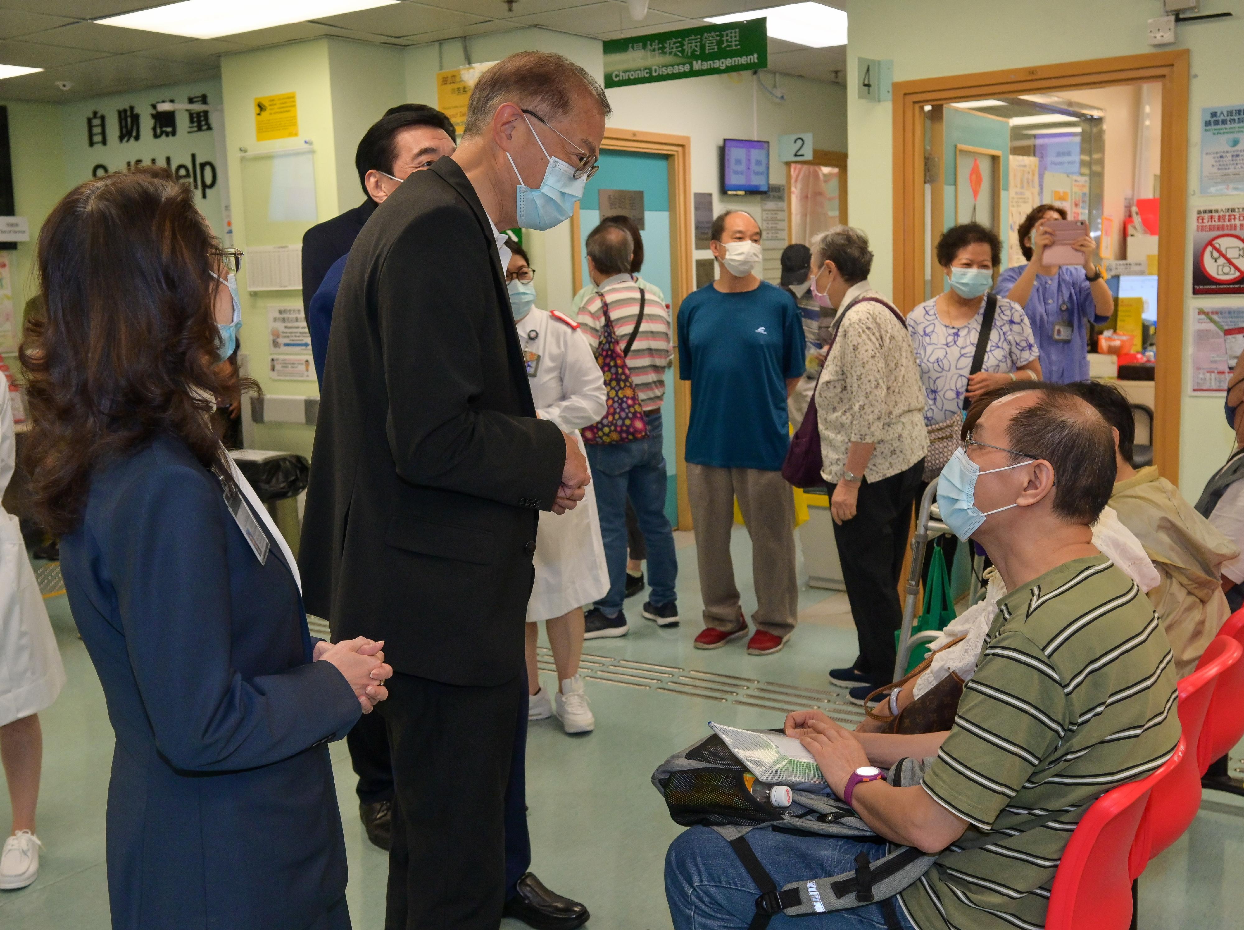 The Secretary for Health, Professor Lo Chung-mau (second left), chats with a citizen before receiving vaccinations against seasonal influenza and COVID-19 at Sai Wan Ho General Out-patient Clinic today (September 24).