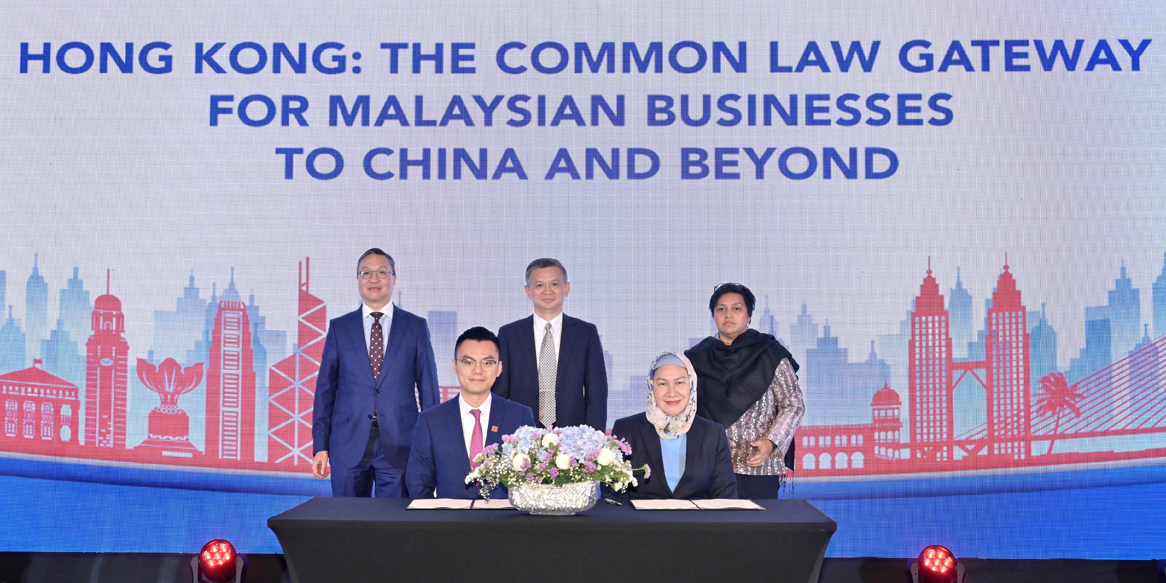 The Secretary for Justice, Mr Paul Lam, SC, leading a delegation comprising representatives from the Law Society of Hong Kong, the Hong Kong Bar Association and alternative dispute resolution organisations, attended a seminar titled Hong Kong: The Common Law Gateway for Malaysian Businesses to China and Beyond, followed by an evening networking reception co-organised by the Department of Justice (DoJ), the Hong Kong Economic and Trade Office in Jakarta and the National Chamber of Commerce and Industry of Malaysia in Kuala Lumpur, Malaysia, on September 26. Photo shows Mr Lam (back row, left); Malaysia's Minister in the Prime Minister's Department (Law and Institutional Reform), Dato' Sri Azalina Othman Said (back row, right); and the Chargé d'Affaires of the Chinese Embassy in Malaysia, Mr Zheng Xuefang (back row, centre), witnessing the signing of a memorandum of understanding facilitated by the DoJ, between the South China International Arbitration Center (HK) and the Asian International Arbitration Centre at the seminar.