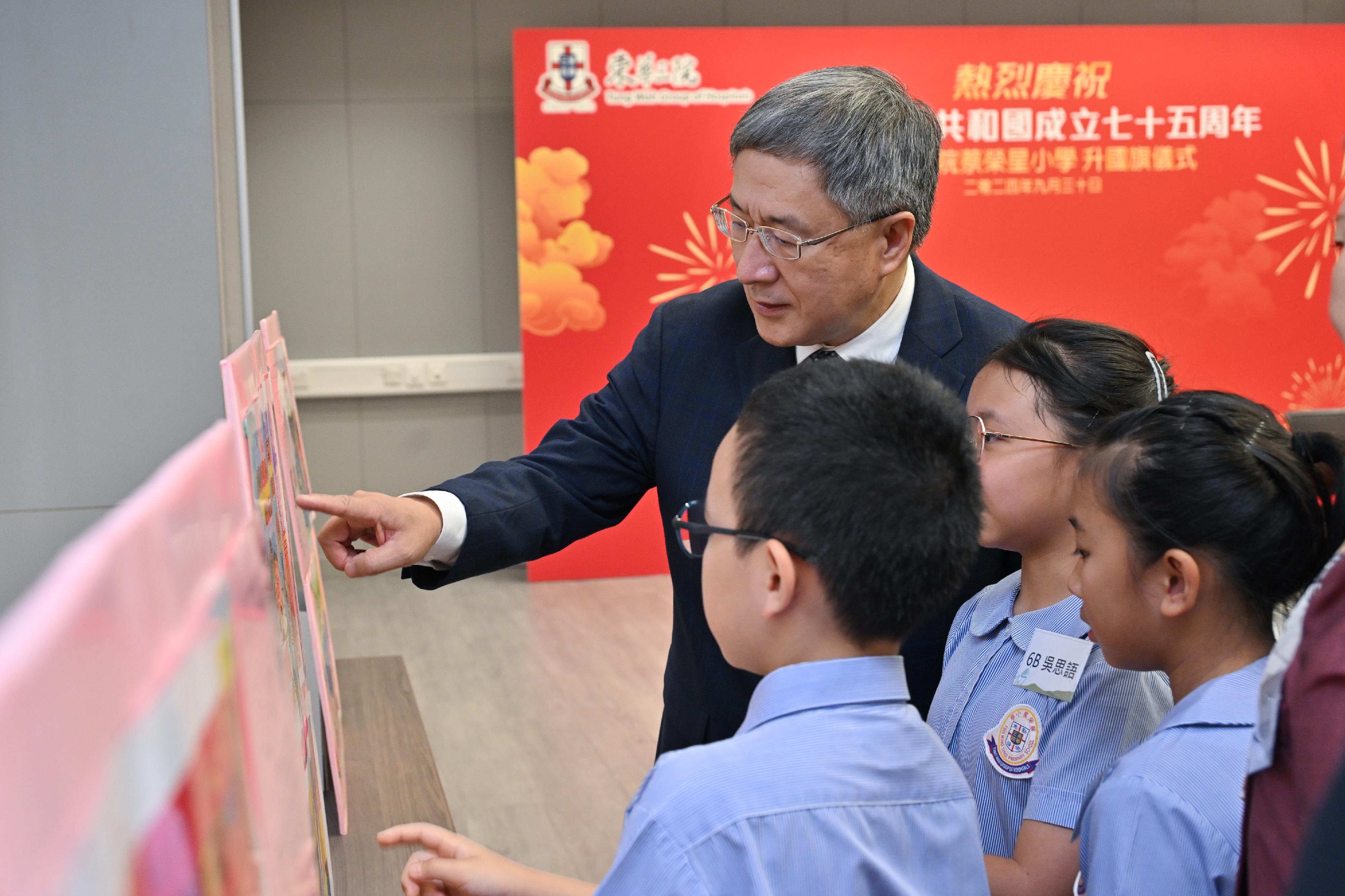 The Deputy Chief Secretary for Administration, Mr Cheuk Wing-hing, chats with students on their National Day celebration activities after attending the national flag-raising ceremony of TWGHs Tsoi Wing Sing Primary School today (September 30).