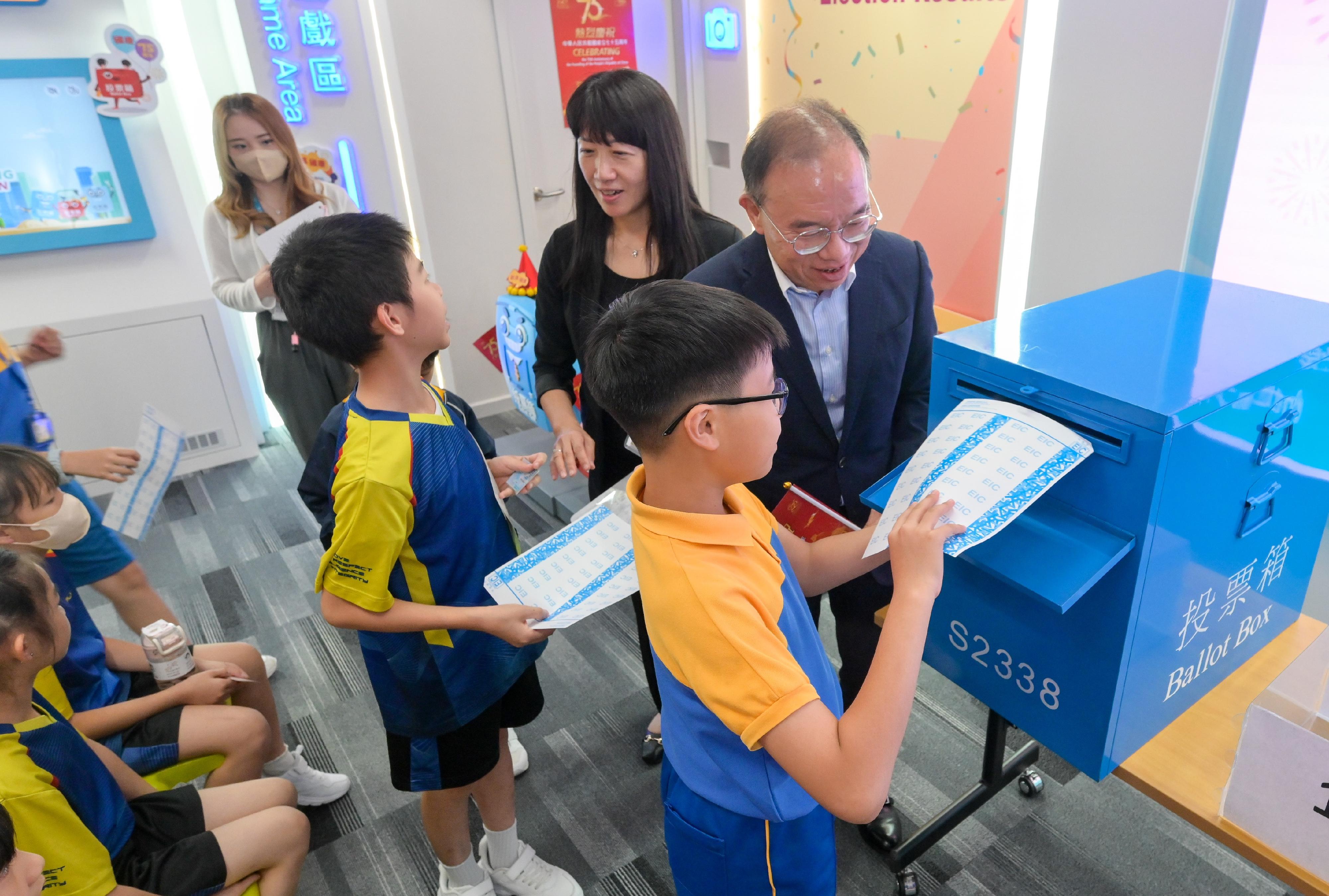 To celebrate the 75th anniversary of the founding of the People's Republic of China, the Electoral Information Centre of the Registration and Electoral Office (REO) is holding National Day Open Days for three consecutive days from today (September 30). The Secretary for Constitutional and Mainland Affairs, Mr Erick Tsang Kwok-wai, attended a guided tour for a group of senior primary school students this afternoon. Photo shows Mr Tsang (back row, first right) participating in the mock polling session with the students experiencing the voting process. Also present was the Chief Electoral Officer of the REO, Ms Natalie Chan (back row, second right).